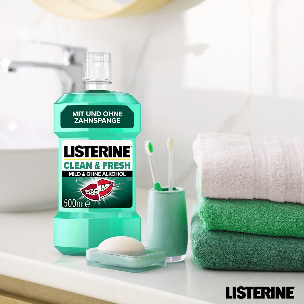 LISTERINE® Clean & Fresh Flasche neben Zahnbürsten, Seife und Handtüchern im Badezimmer.