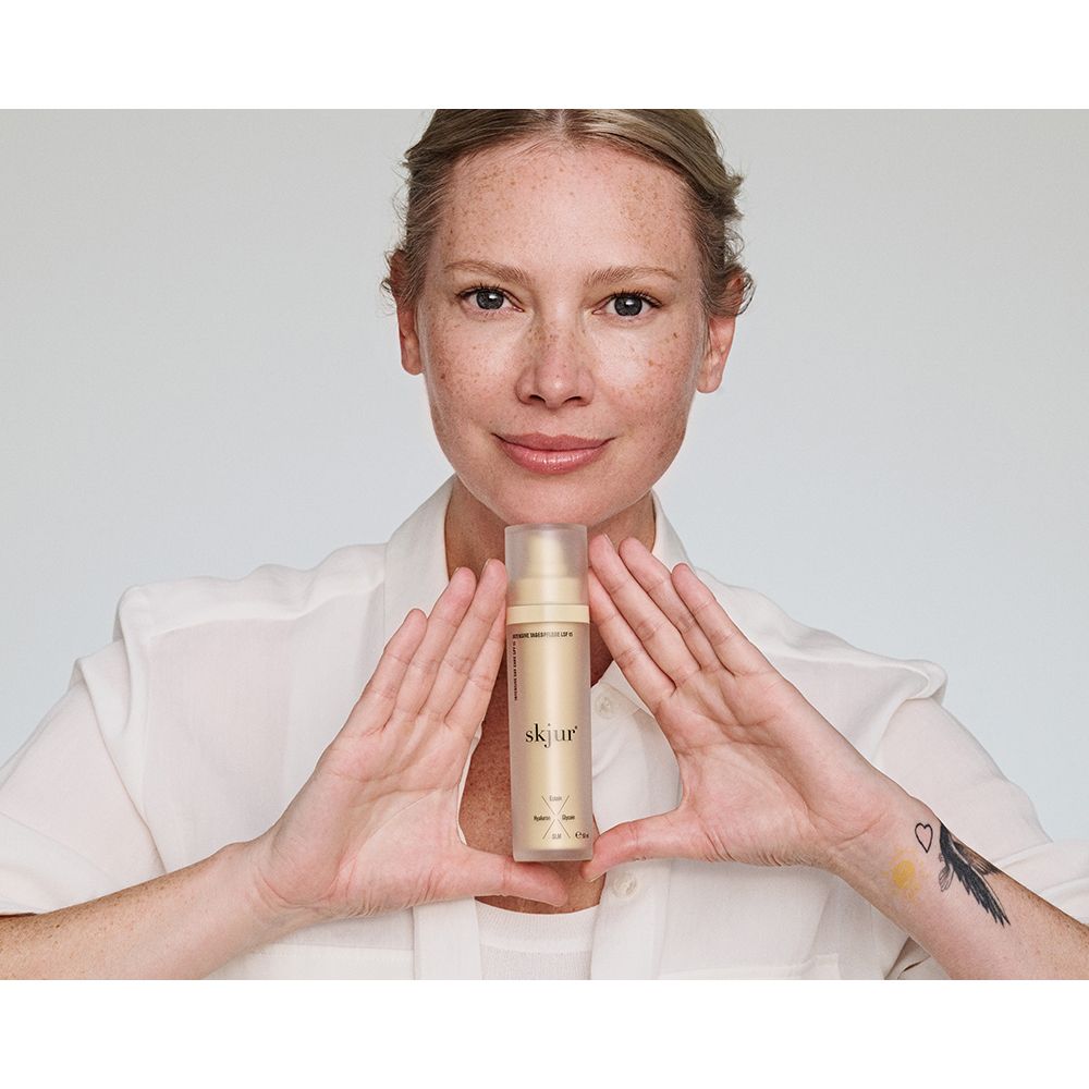 Goldene Flasche mit Pumpspender, gehalten von einer Frau.