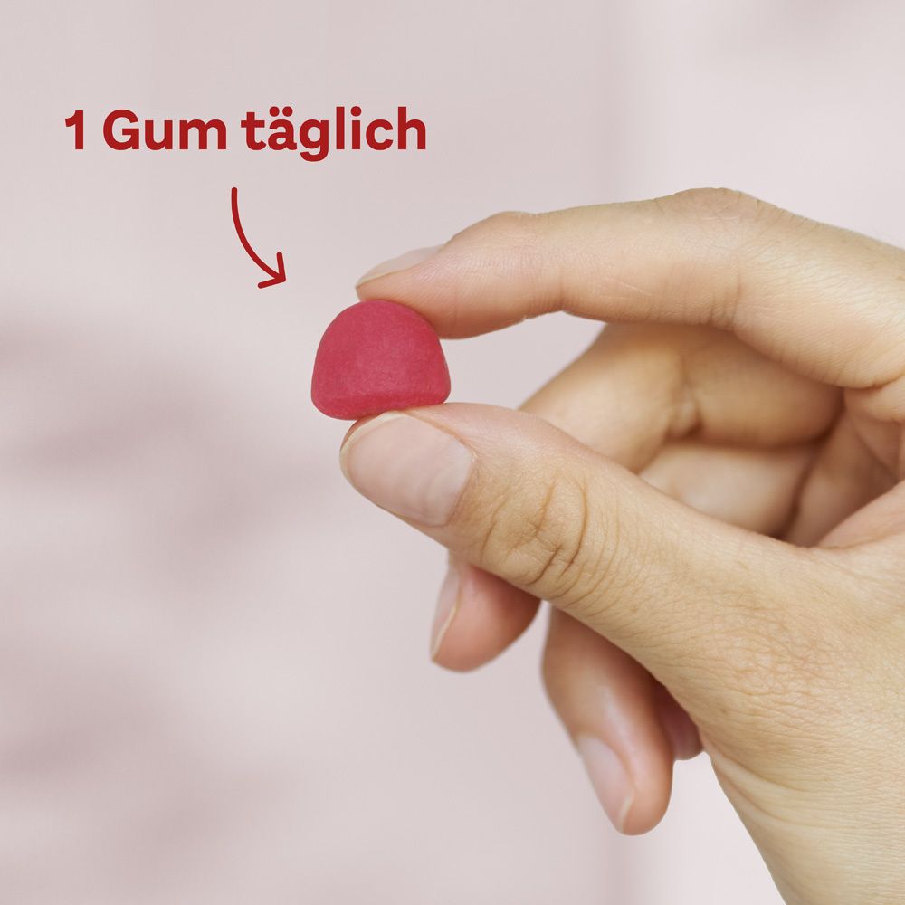 Hand hält ein rotes Gummibärchen. Text: 1 Gum täglich. Produkt: Doppelherz aktiv Haut + Haare + Nägel Gums.