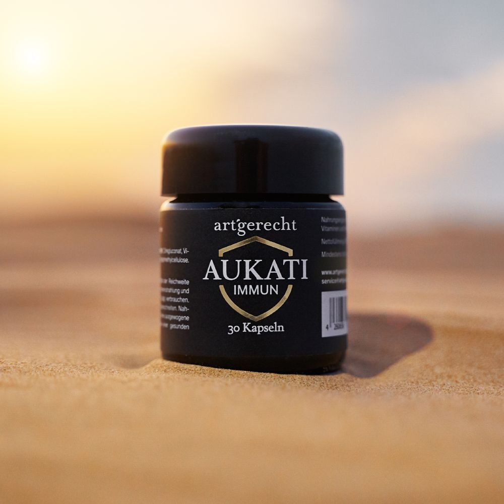 Schwarze Dose mit Aufschrift AUKATI IMMUN, 30 Kapseln, auf Sand. Schwarzer Deckel.