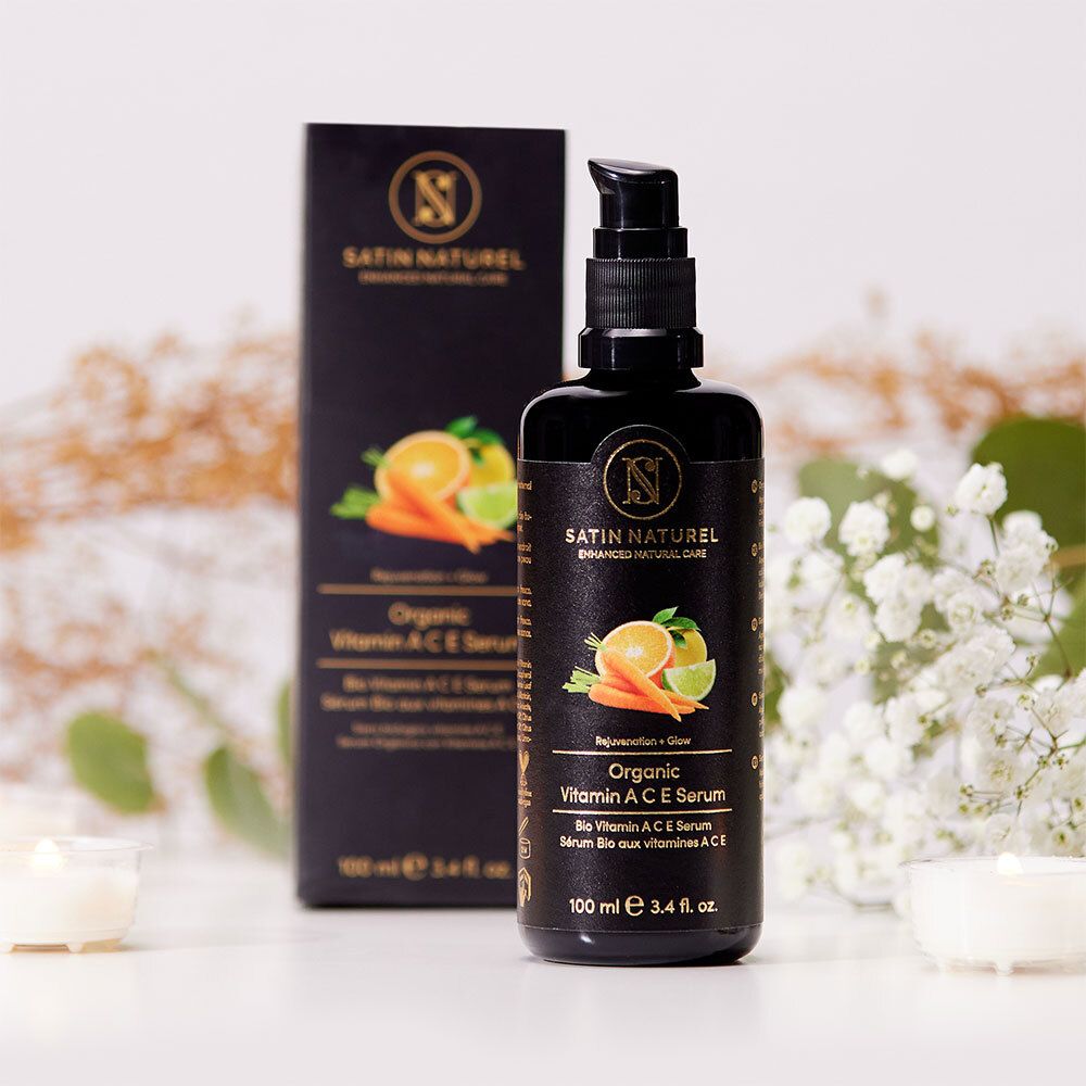 Schwarze Flasche und Schachtel mit Blumen. Aufschrift: SATIN NATUREL, Organic Vitamin A C E Serum. 100 ml.