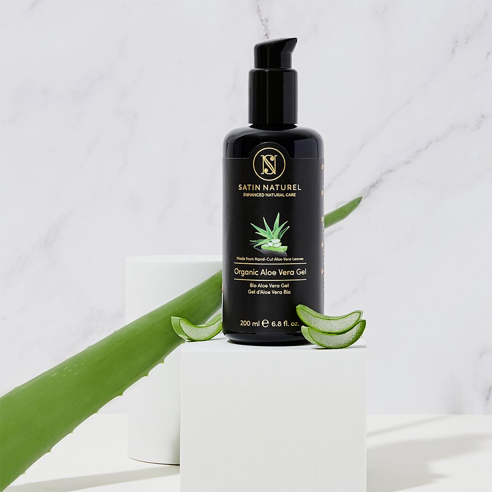 SATIN NATUREL Bio Aloe Vera Gel Flasche auf Würfel mit Aloe Vera Blättern.