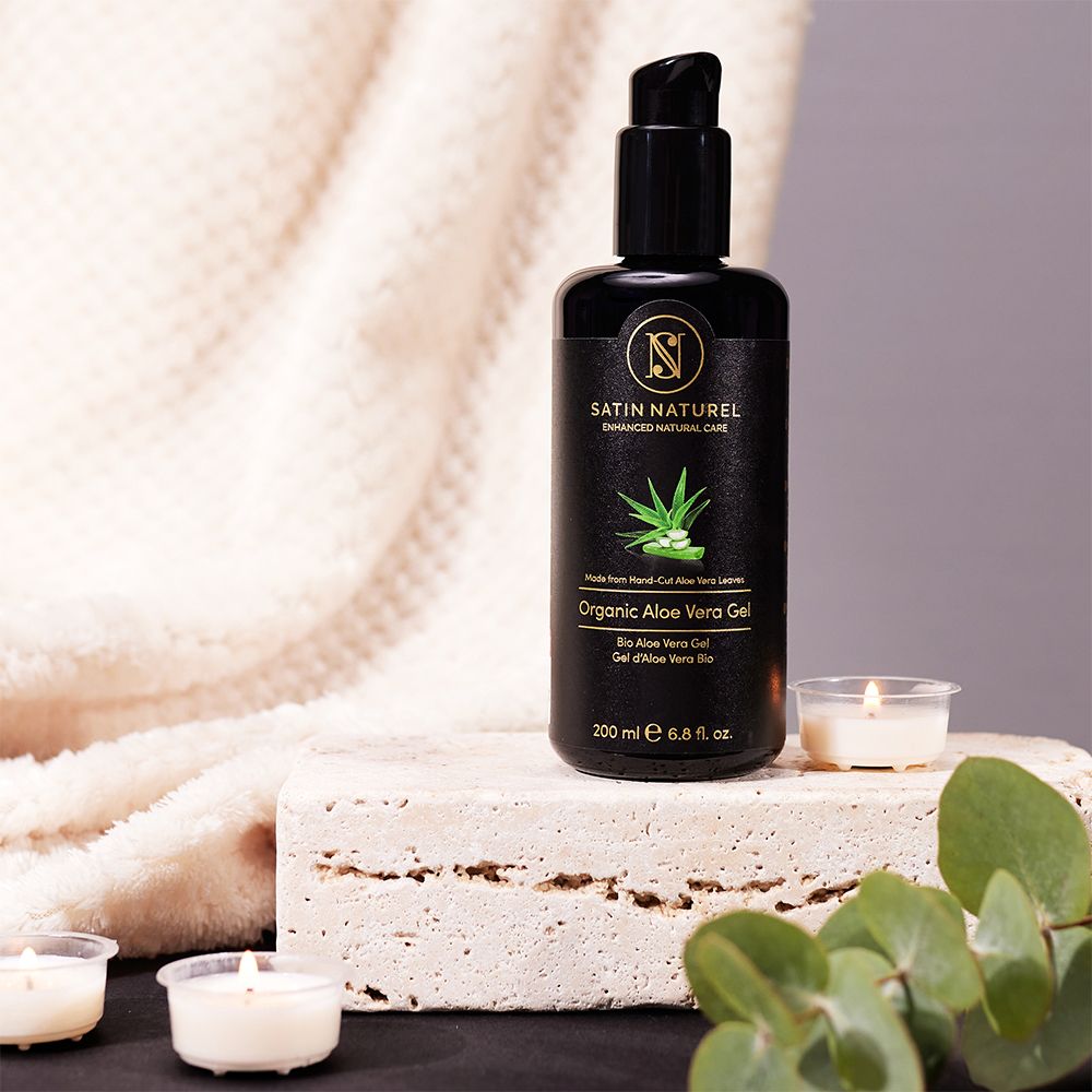 SATIN NATUREL Bio Aloe Vera Gel Flasche auf Steinblock mit Kerzen und Eukalyptus.