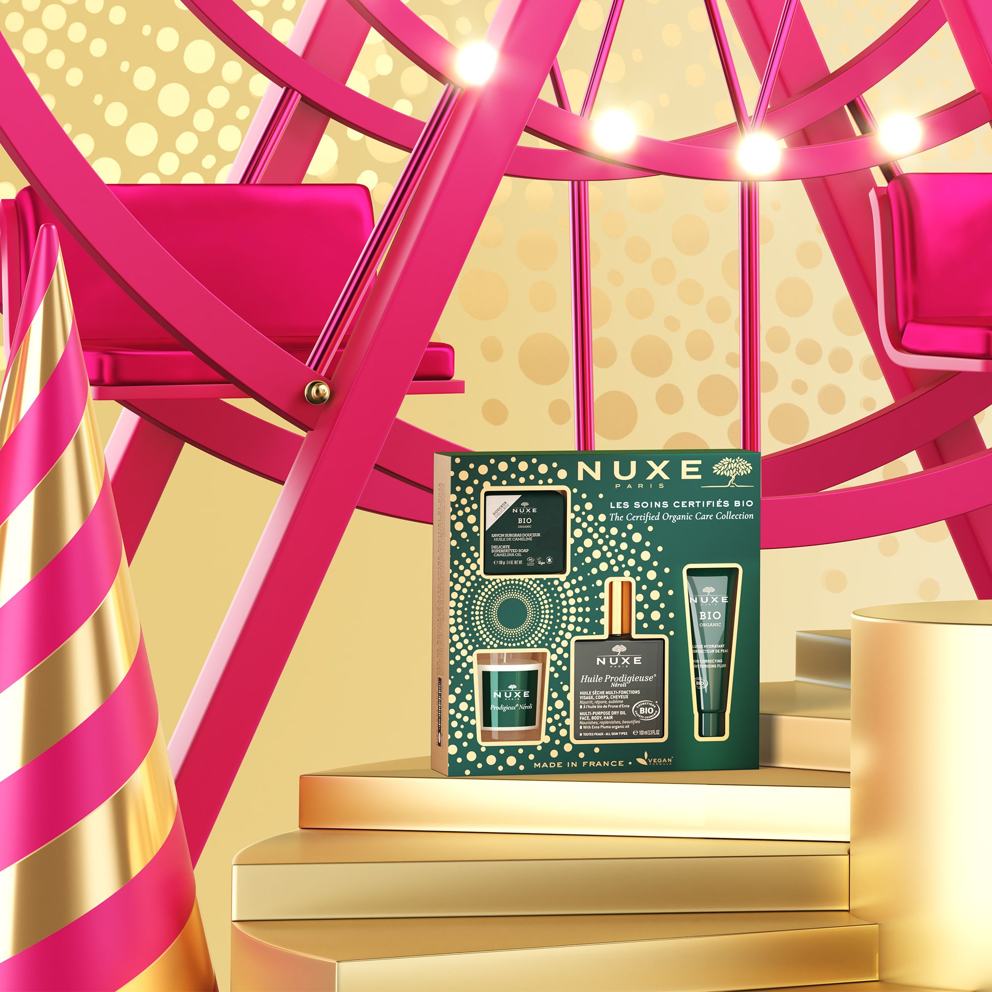 Geschenkset mit NUXE Bio-Produkten auf goldenen Podesten. Hintergrund: Jahrmarkt mit Riesenrad.