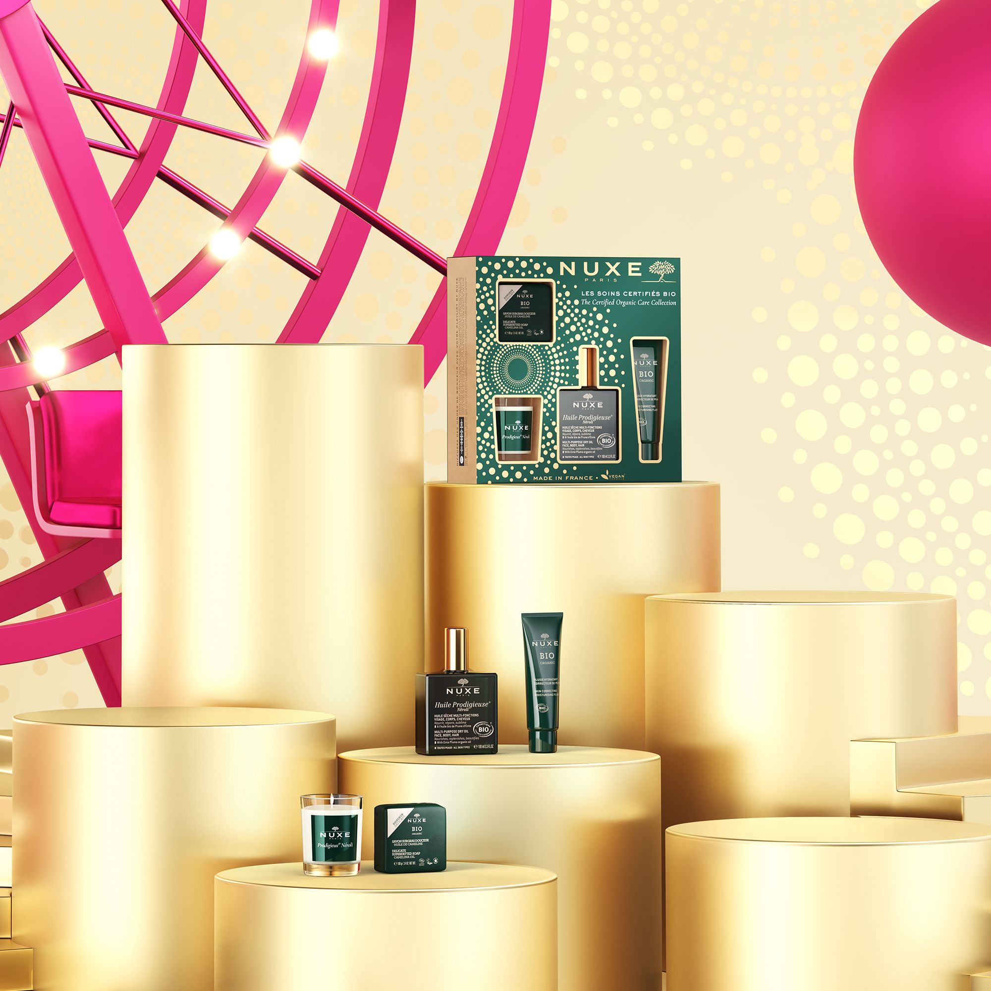 Geschenkset mit NUXE Bio-Produkten auf goldenen Podesten. Hintergrund: Jahrmarkt mit Riesenrad.