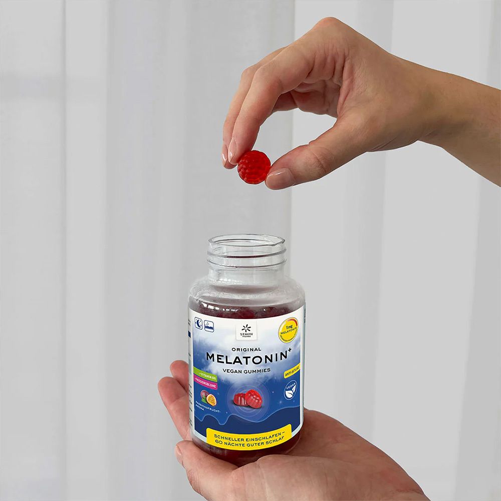 Hände halten eine Flasche und ein Gummibärchen. Aufschrift: Original Melatonin+ Vegan Gummies.