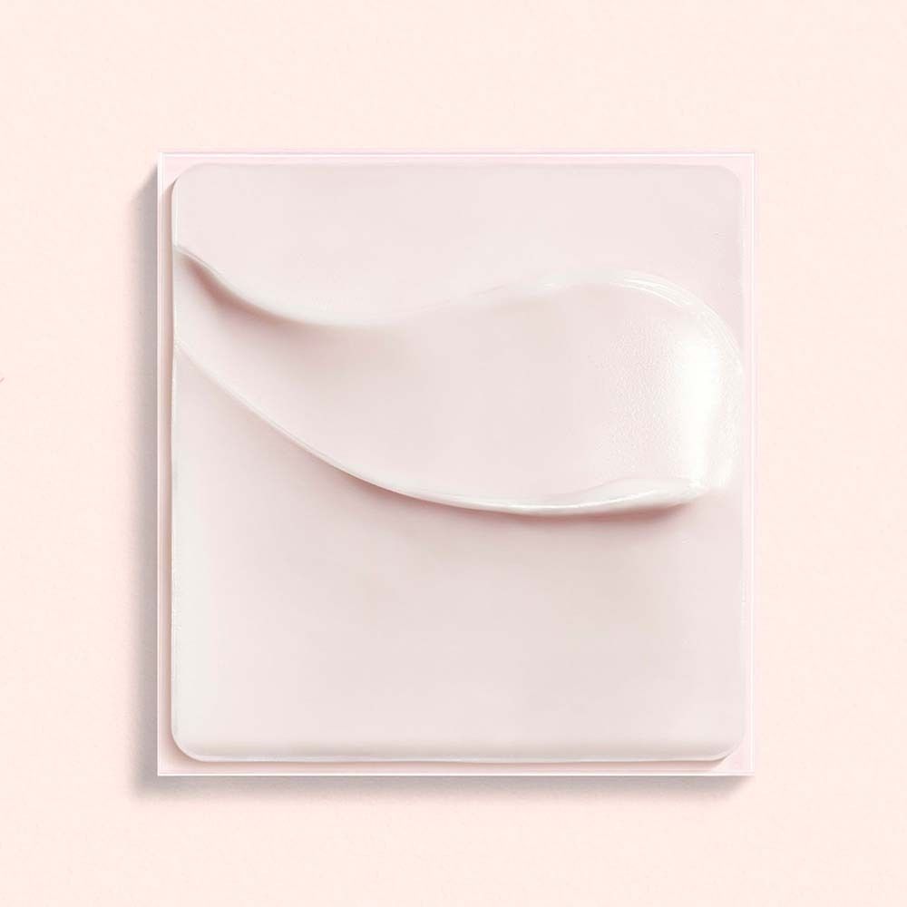 Rosa Creme auf quadratischer Unterlage. Creme-Textur sichtbar.