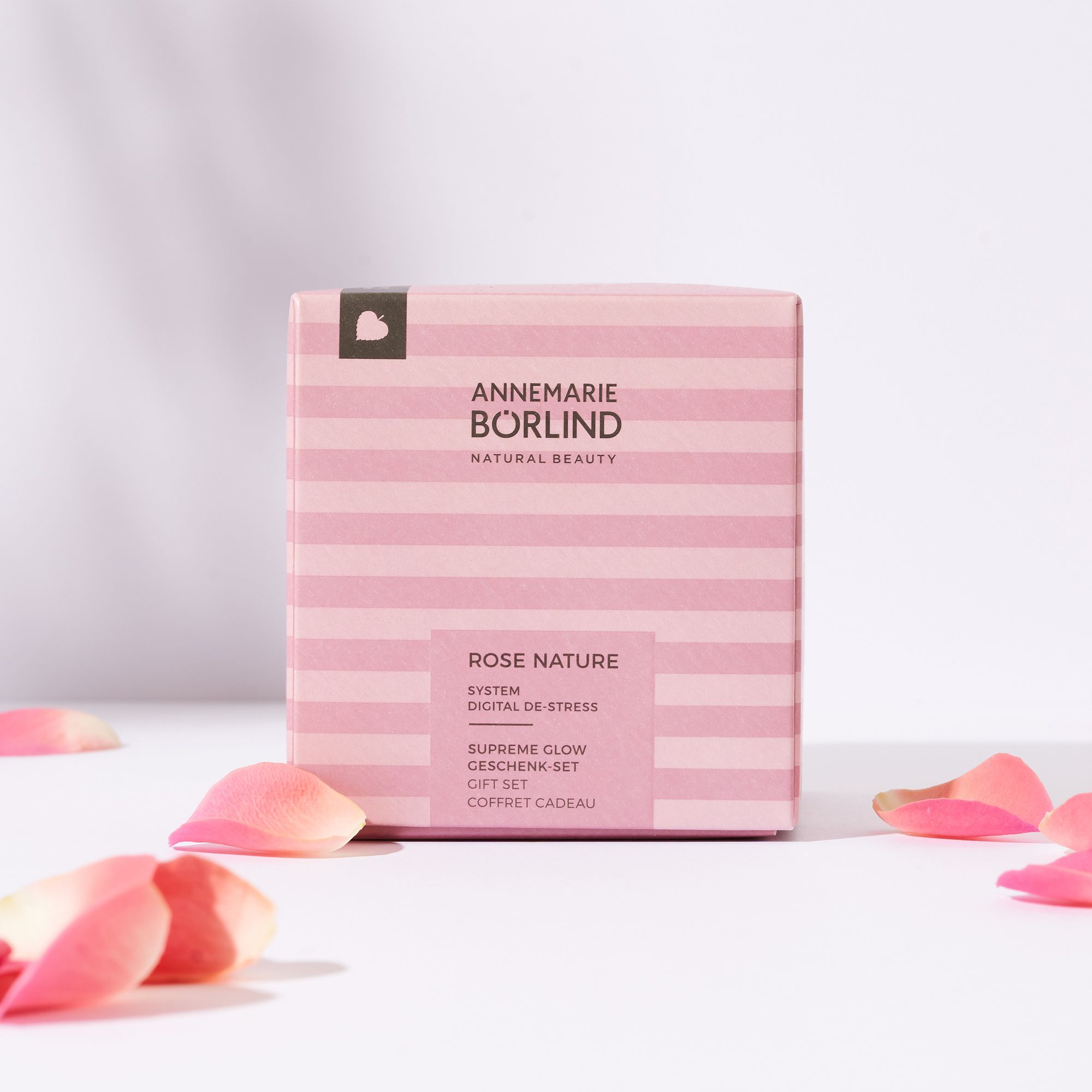 Rosa Geschenkbox mit Streifenmuster. Rosenblätter liegen um die Box herum. Aufschrift: Annemarie Börlind.