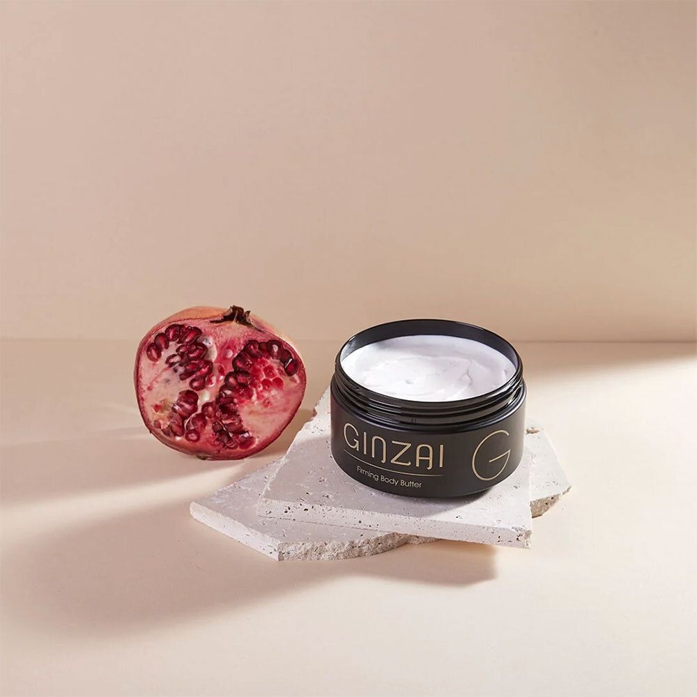 Offener Tiegel mit weißem Inhalt. Daneben eine Granatapfelhälfte. Auf Steinplatte.