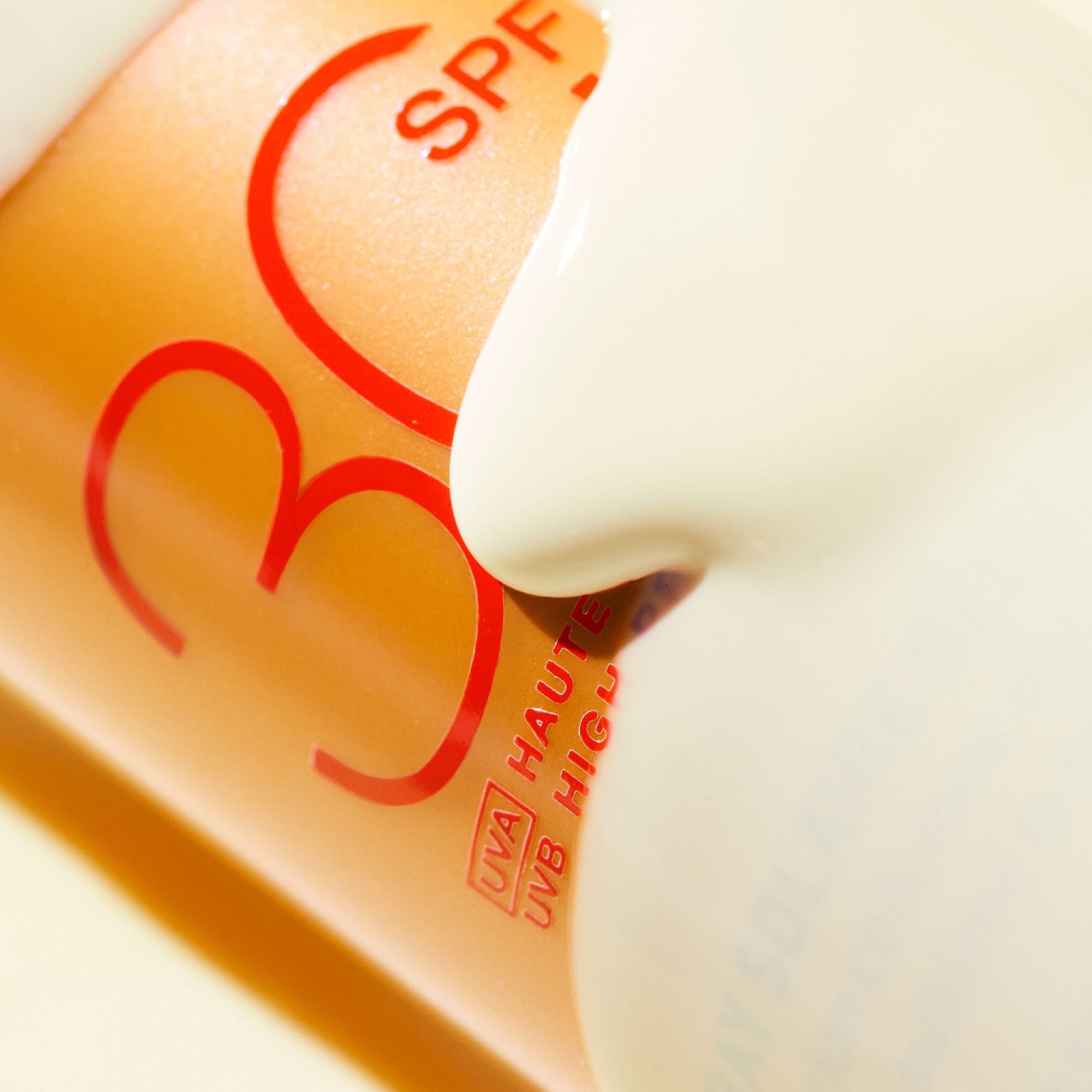 Nahaufnahme von Sonnencreme, die aus einer Flasche kommt. Text: SPF 30. UVA Haute Protection, UVB High Protection.