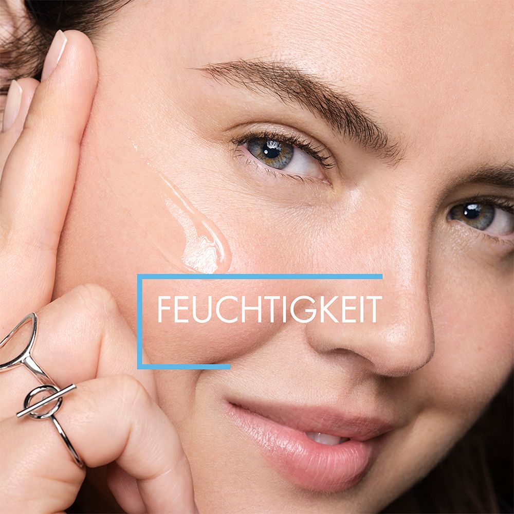 Nahaufnahme eines Gesichts. Ein Tropfen Serum auf der Haut. Text: FEUCHTIGKEIT.