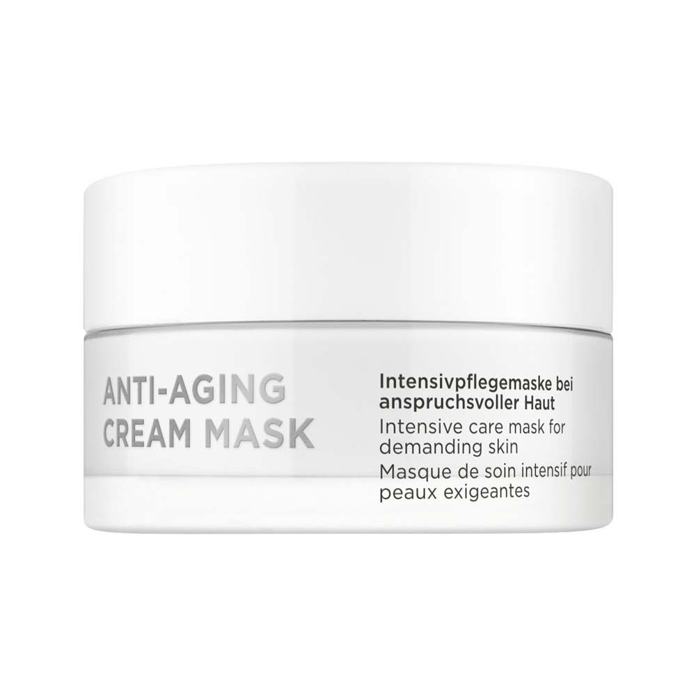 Weiße Creme-Maske in einem weißen Tiegel. Aufschrift: ANTI-AGING CREAM MASK. Text in Deutsch, Englisch und Französisch.