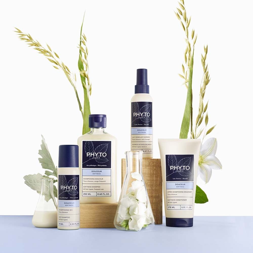 Verschiedene PHYTO PARIS Produkte, darunter Trockenshampoo, in weiß-blauen Flaschen. Dekoration mit Pflanzen.
