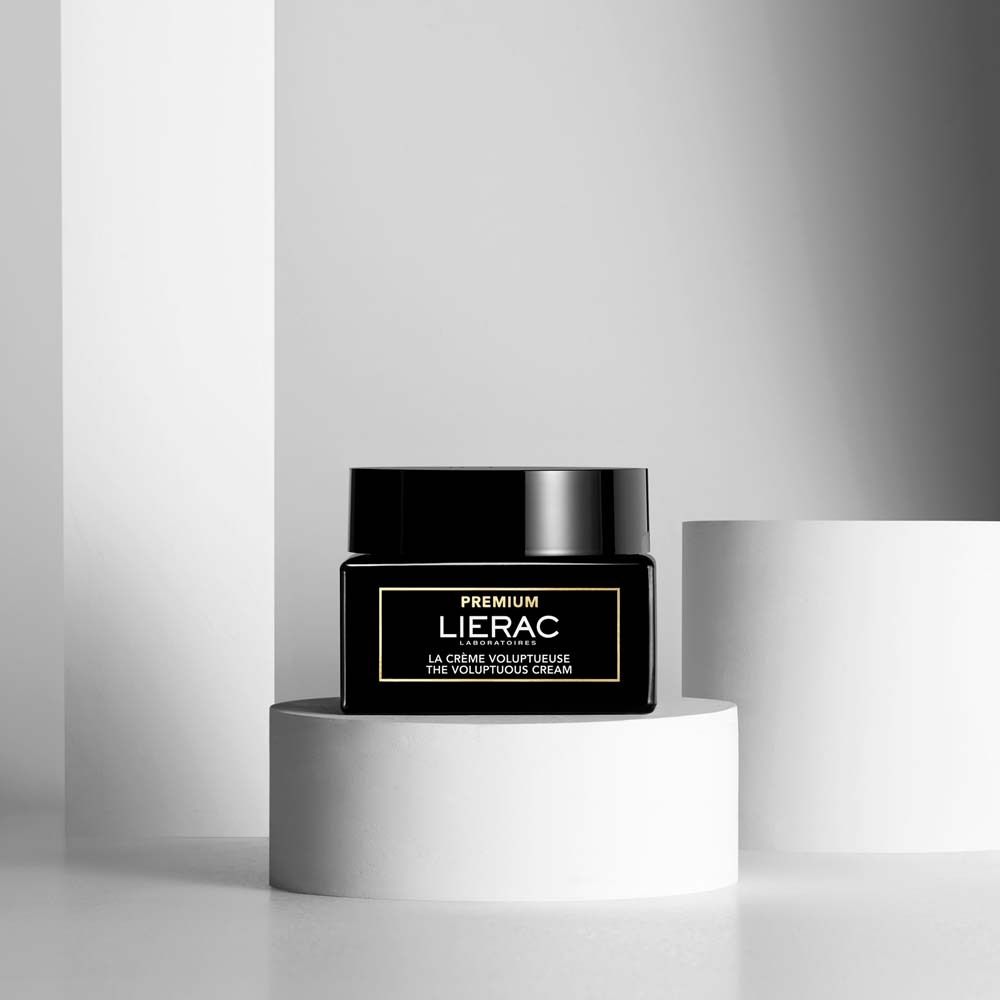Schwarzer Tiegel mit Deckel auf weißem Podest. Aufschrift: PREMIUM LIERAC. Text: LA CRÈME VOLUPTUEUSE.