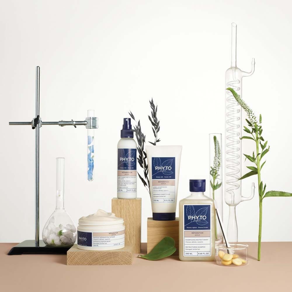 Produkt-Arrangement mit Flaschen, Tiegeln und Pflanzen. Produkte: PHYTO PARIS. Auf Holzblöcken, vor Laborutensilien.