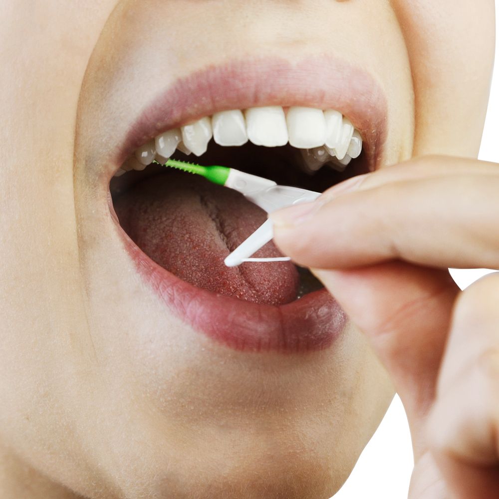 Person verwendet einen Mara expert® FlossSTX Zahnseide-Stick im Mund. Der Stick wird zwischen den Zähnen geführt, um diese zu reinigen.