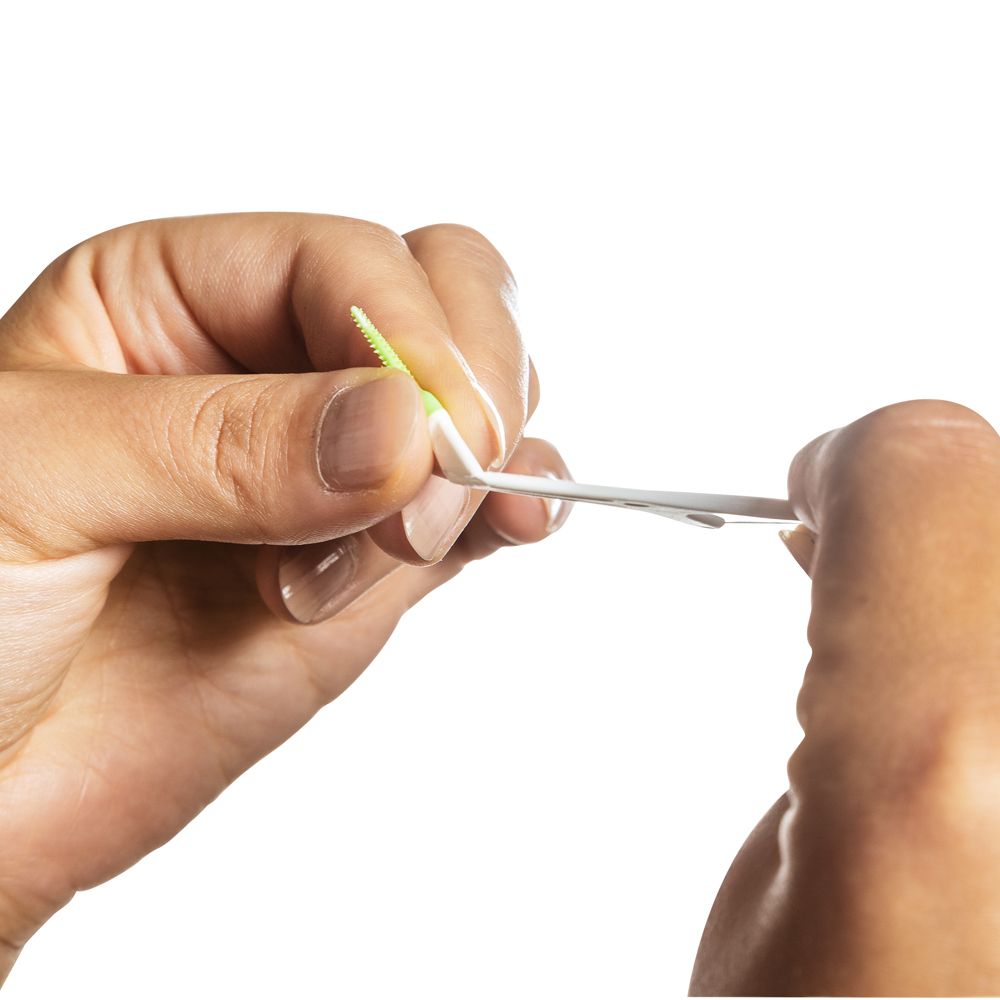 Nahaufnahme von Händen, die einen Mara expert® FlossSTX Zahnseide-Stick halten. Der Stick wird zwischen den Fingern gehalten.
