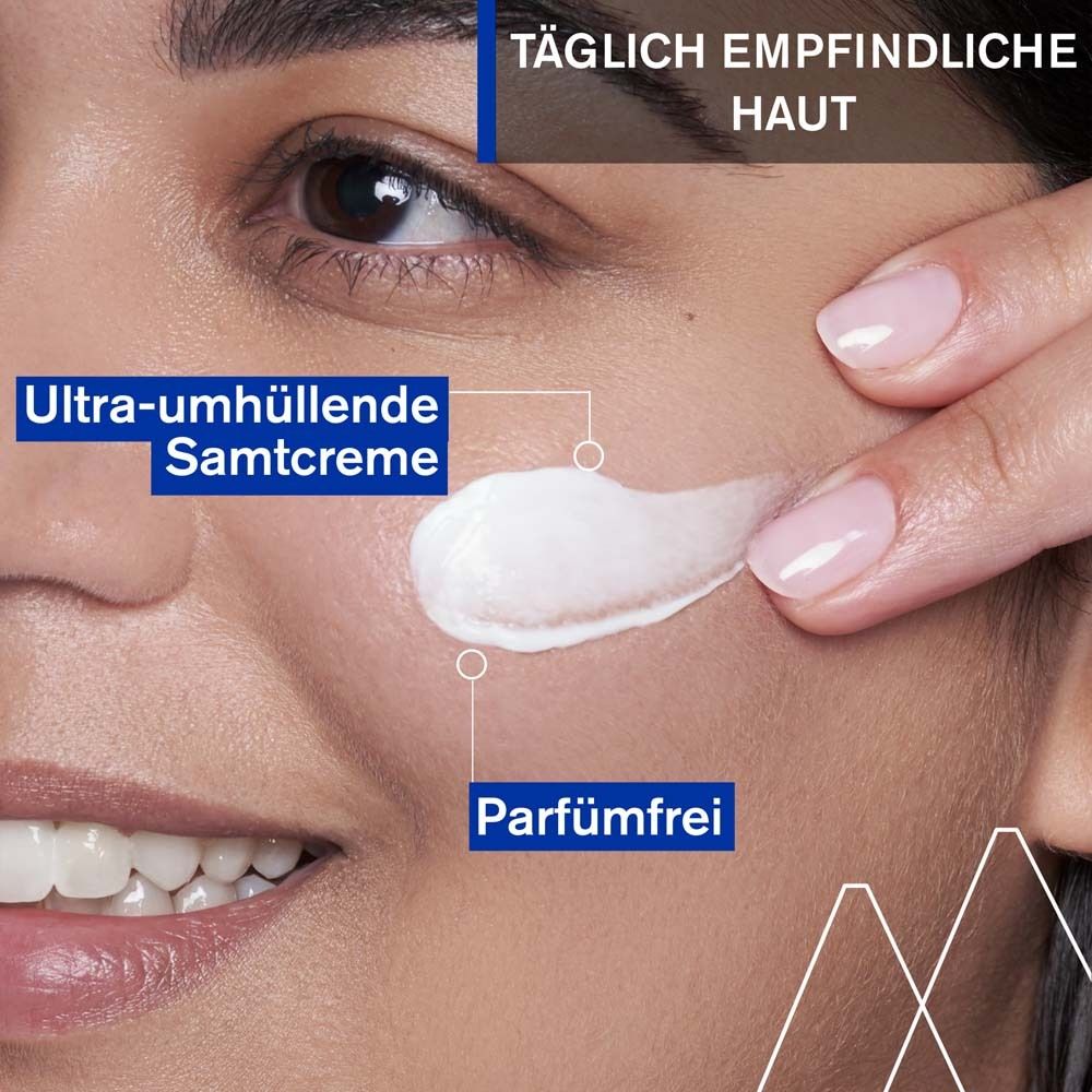 Nahaufnahme einer Frau, die Creme auf ihr Gesicht aufträgt. Text: Ultra-umhüllende Samtcreme, parfümfrei.