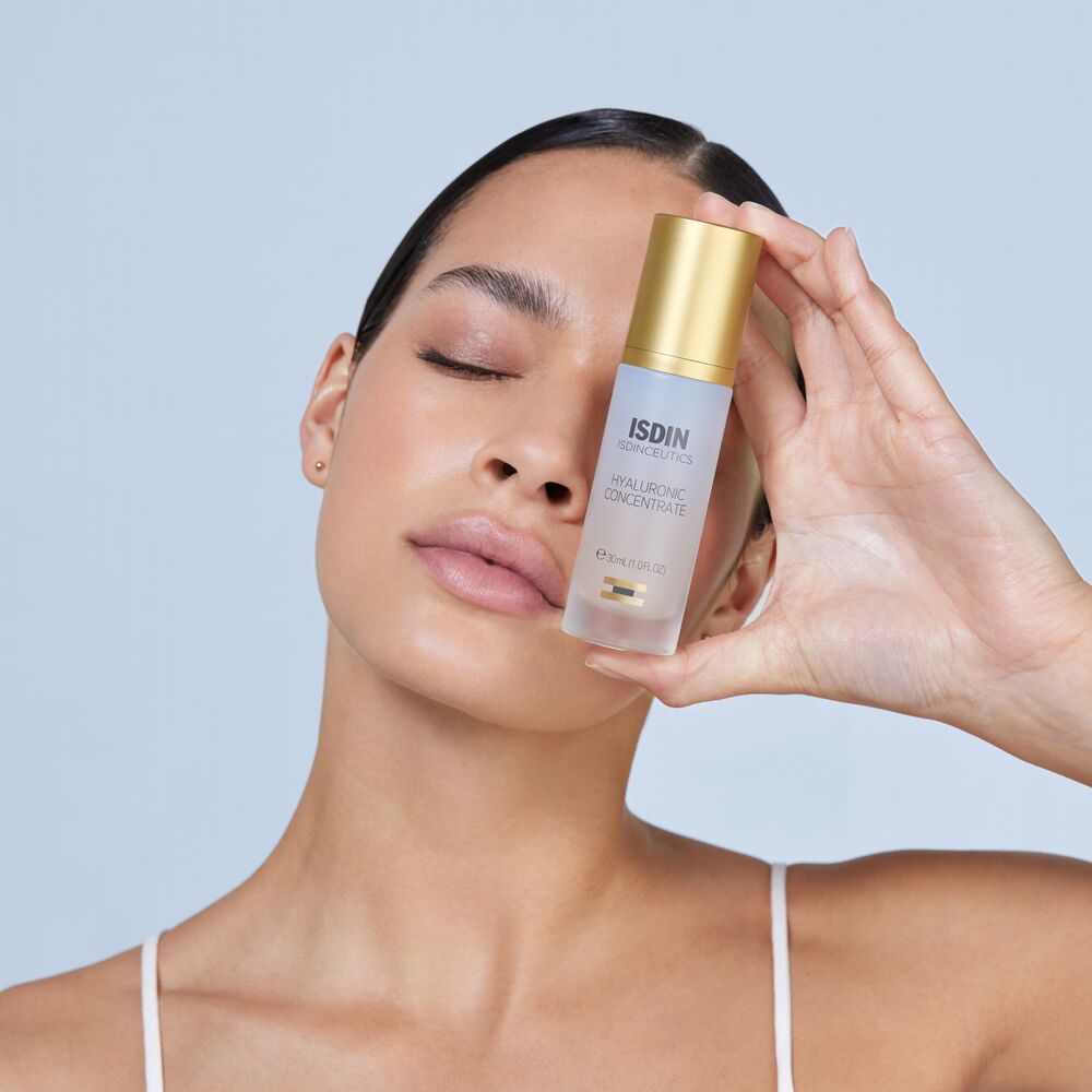 Frau hält Isdin Hyaluronic Concentrate Serum vor ihr Gesicht.