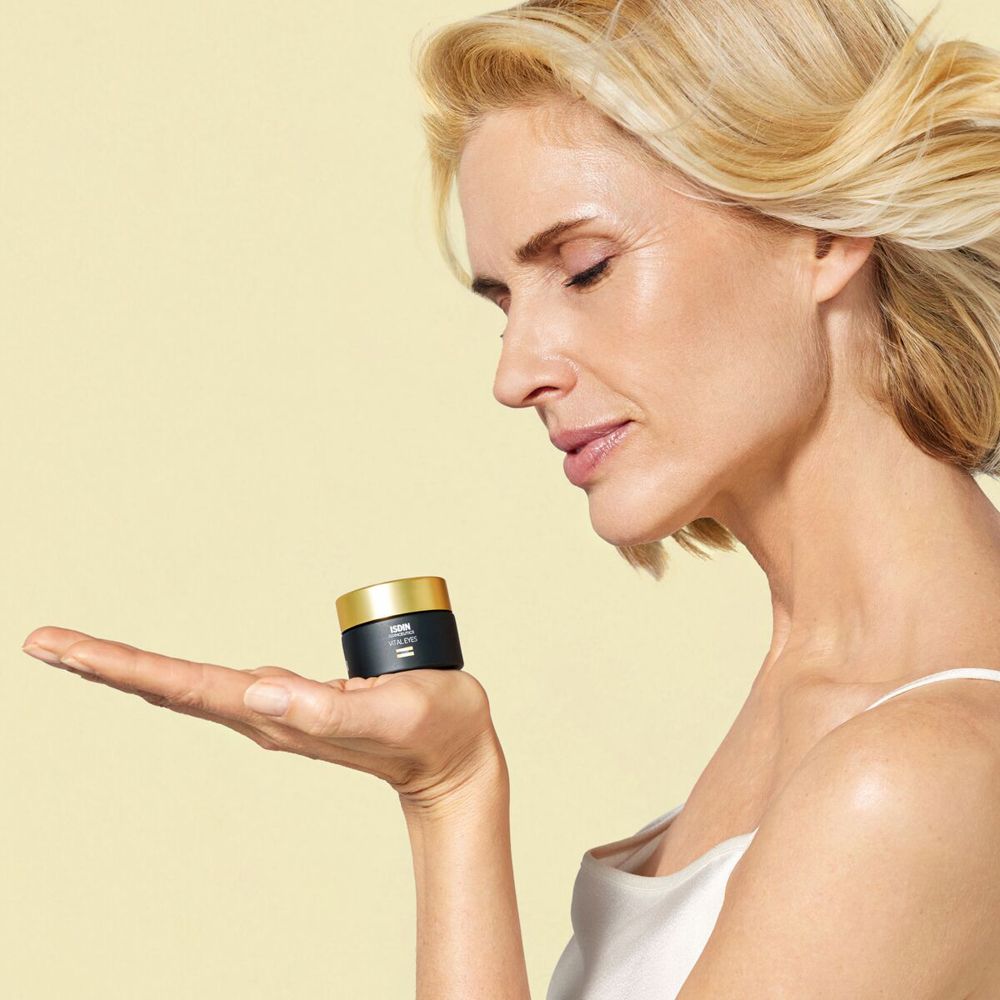 Frau hält einen schwarzen Tiegel mit goldfarbenem Deckel in der Hand. Produktname: Vital Eyes.