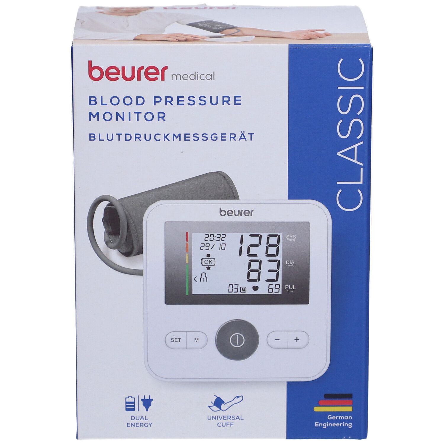 Blutdruckmessgerät in Verpackung. Weißes Gerät mit Display, Manschette, Logo. Text: Beurer, Blutdruckmessgerät, Classic.