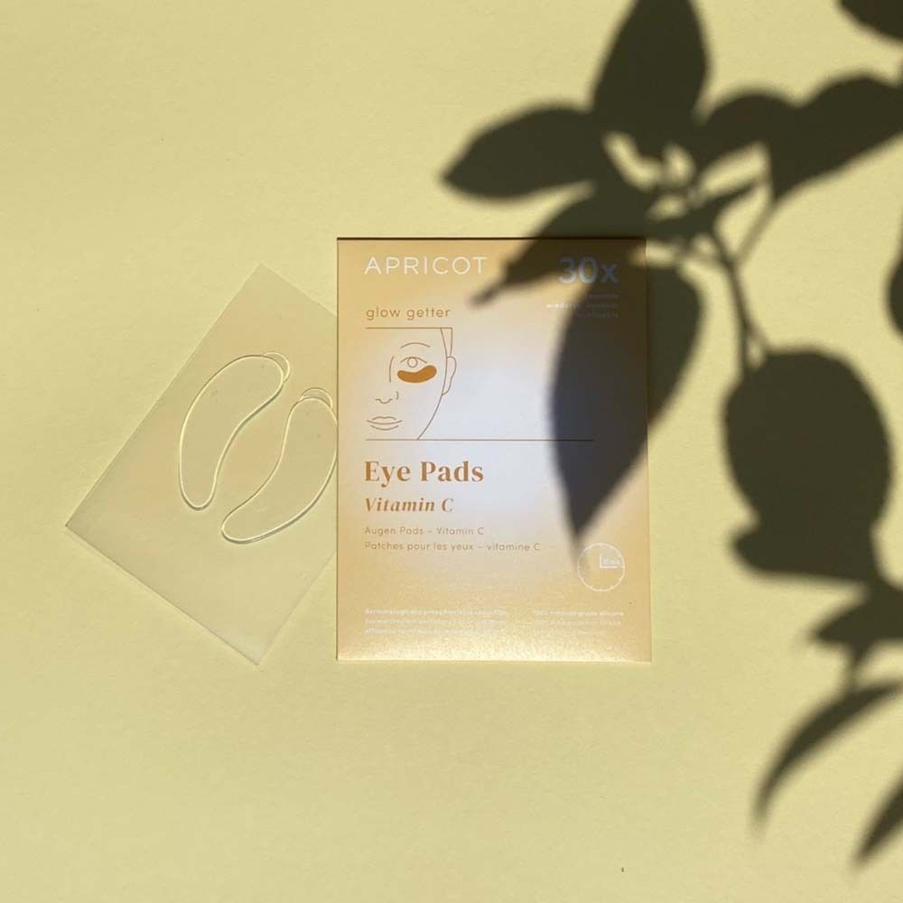 Verpackung mit Augen Pads und zwei Pads daneben. Aufgedruckt: APRICOT, Eye Pads Vitamin C.