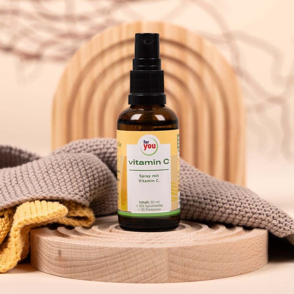 Braune Sprühflasche 'for you vitamin C' auf Holz. Im Hintergrund Holzdekor und Textil.