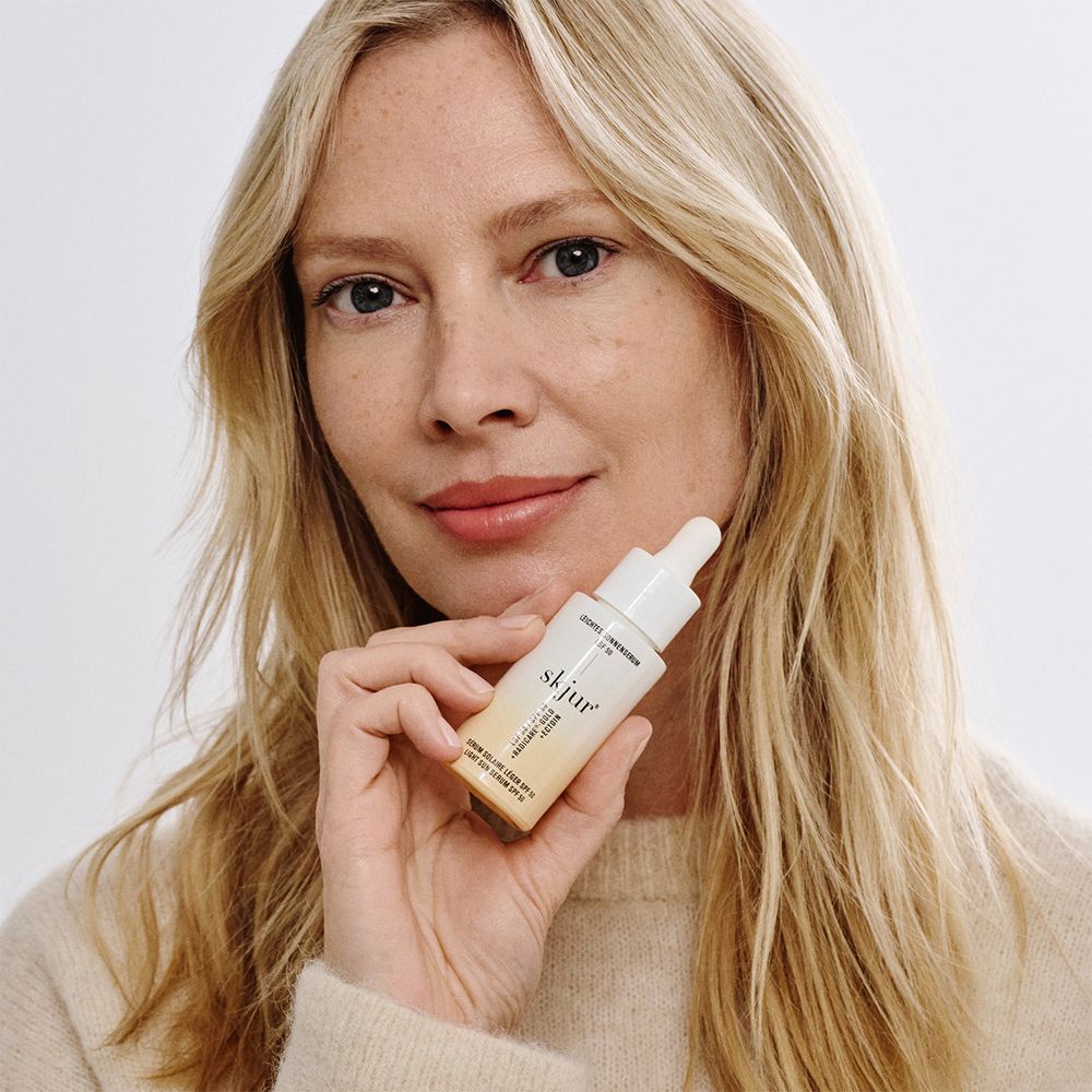 Frau hält skjur leichtes Sonnenserum LSF 50 Flakon.