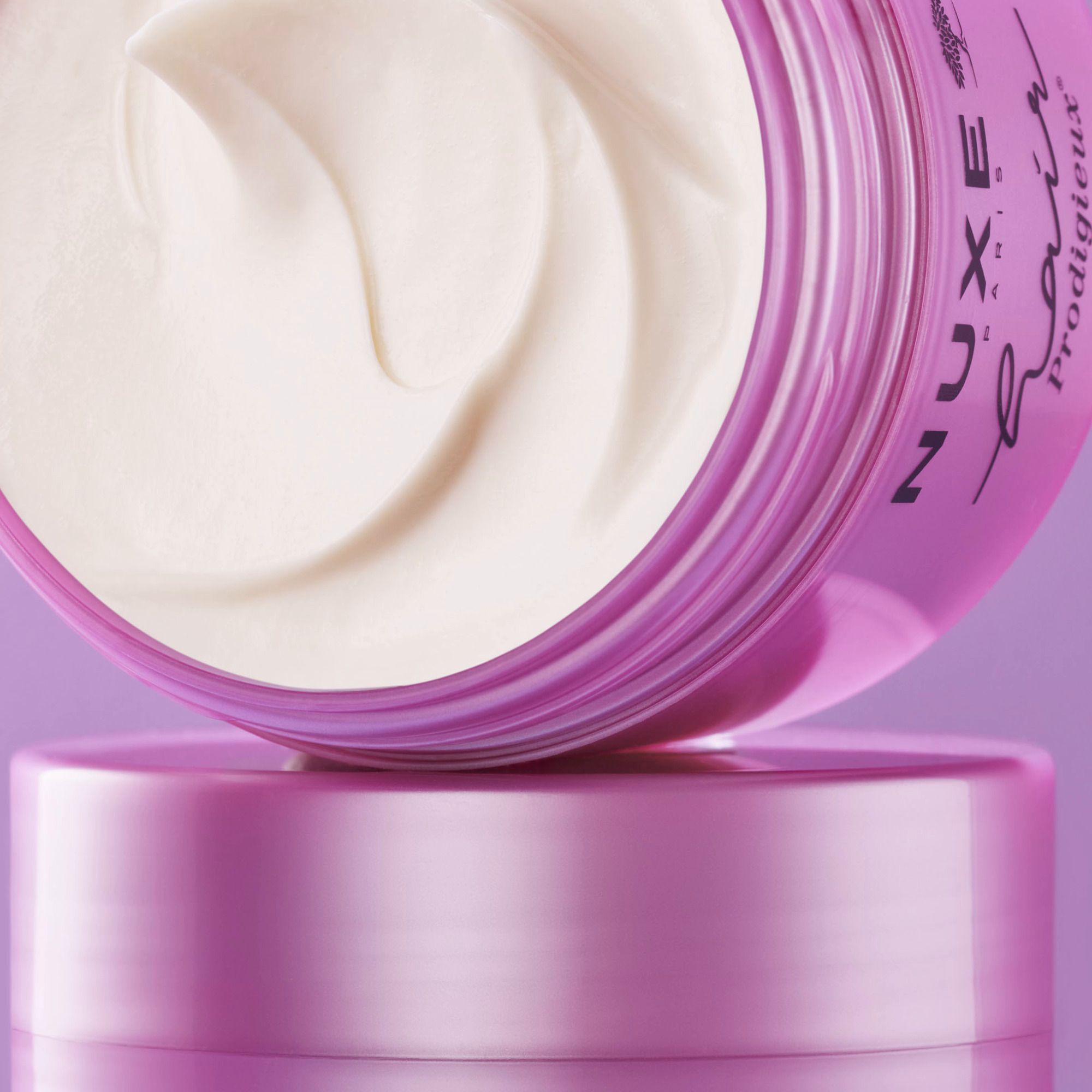 Nahaufnahme einer rosa Dose mit weißer Creme. NUXE-Logo und Schriftzug sind sichtbar.