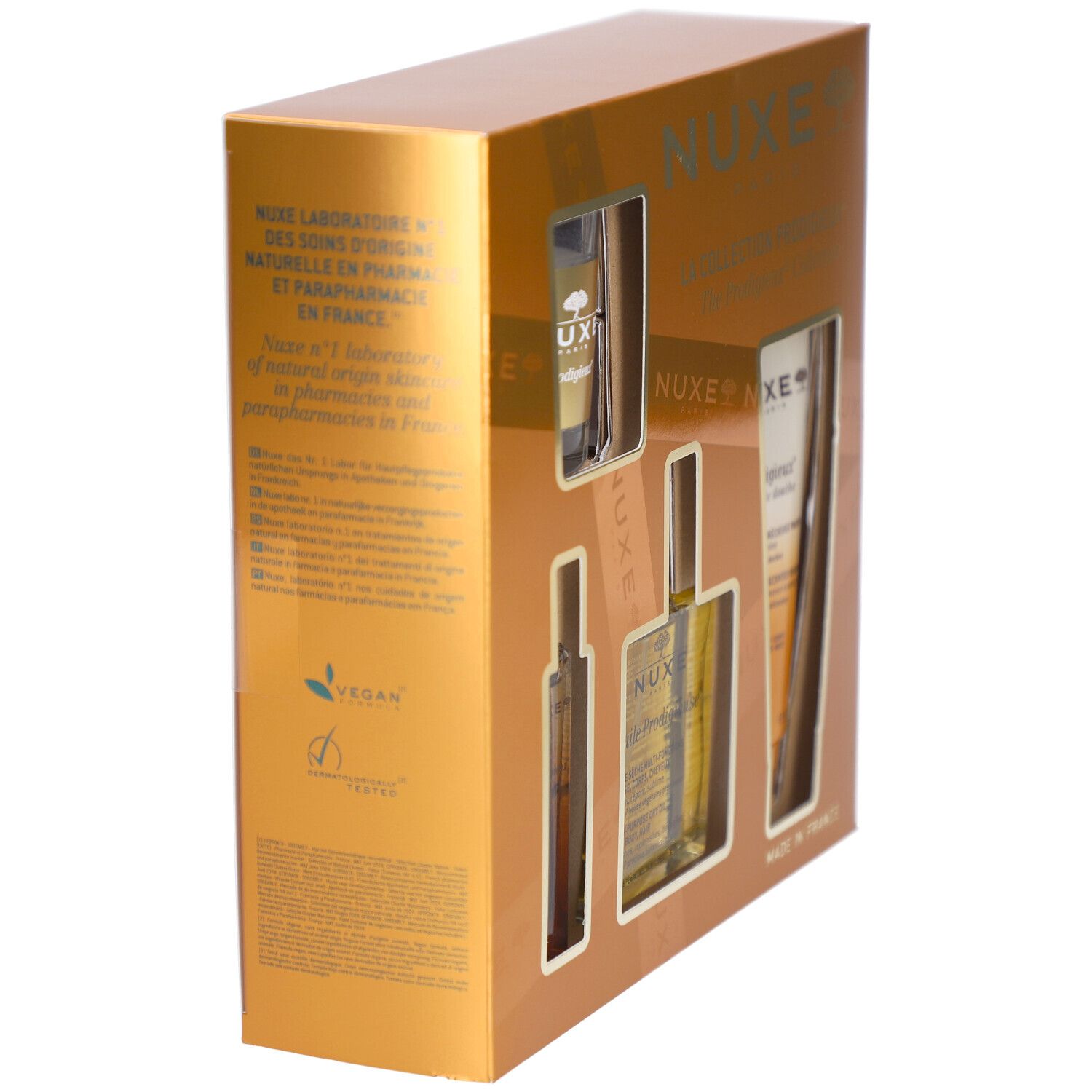 Goldene Geschenkbox mit Produkten. Sichtbar sind Flaschen, eine Tube und ein Glas. Text: NUXE, Vegan-Logo, Made in France.