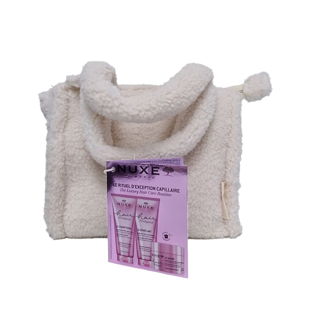 Cremefarbene Tasche mit Henkeln und Anhänger. Anhänger zeigt Abbildung von Haarprodukten. NUXE Hair Prodigieux.