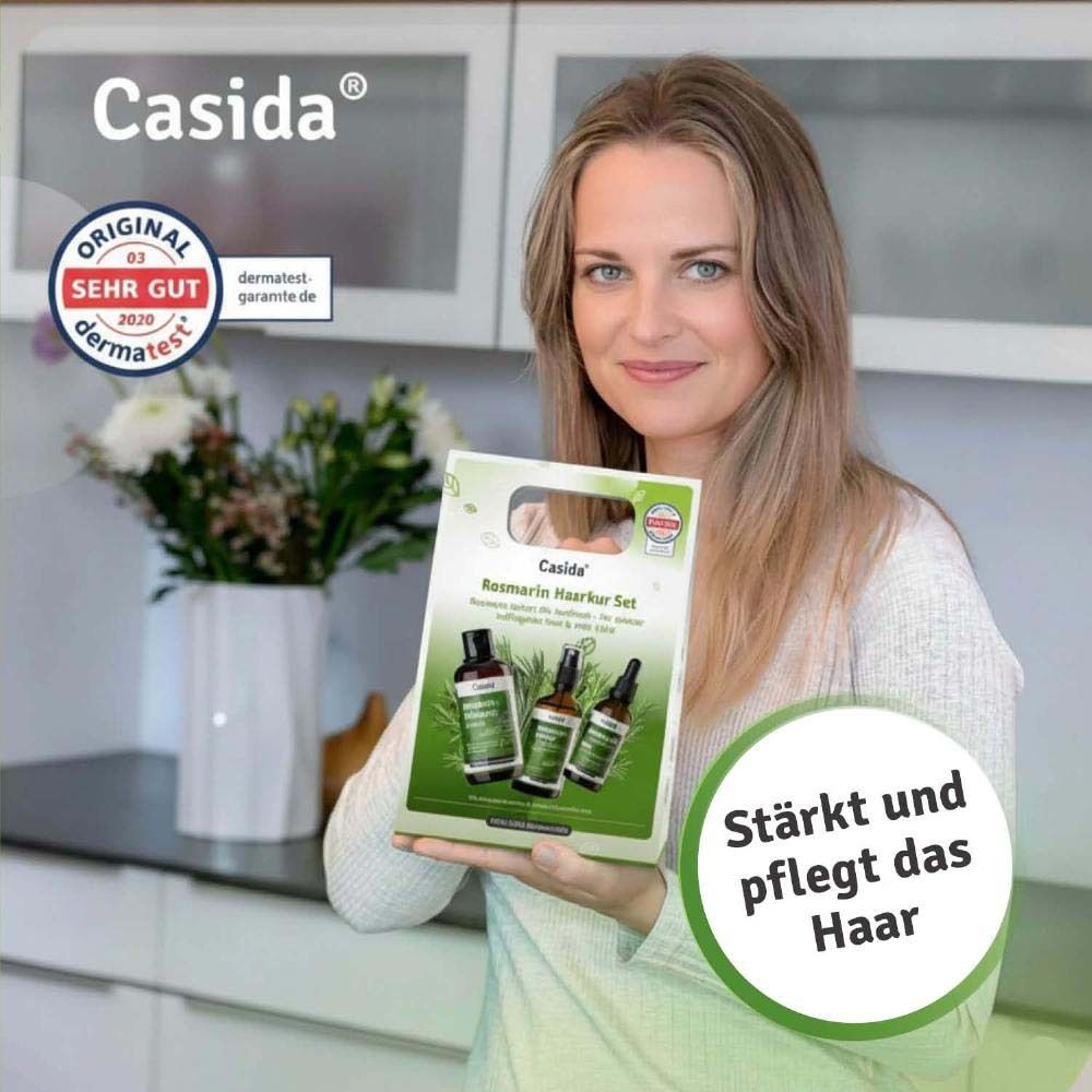 Frau hält eine Casida Rosmarin Haarkur Set-Verpackung. Text: Stärkt und pflegt das Haar. Logo: Original 03 2020 dermatest.