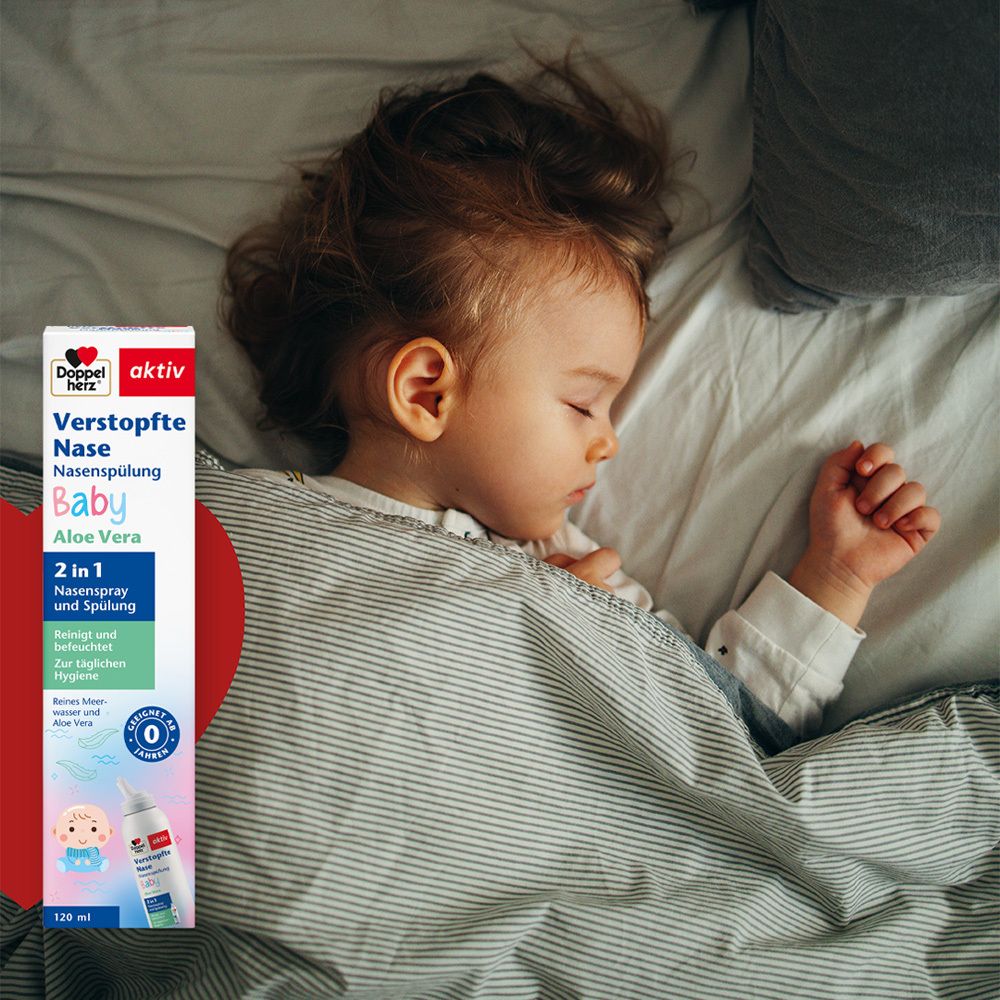 Baby schläft im Bett. Doppelherz aktiv Nasenspray Baby. Produktverpackung im Bildausschnitt.