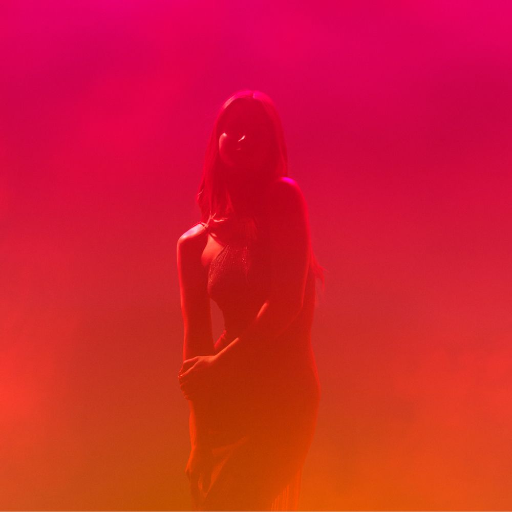 Person vor rotem und orangenem Hintergrund. Nur Silhouette sichtbar.