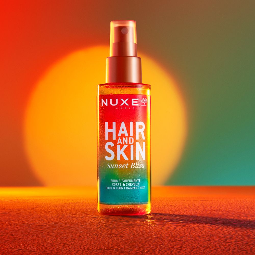 NUXE® Hair and Skin Sunset Bliss. Farbverlauf-Flasche mit Sprühkopf. Text: Hair and Skin, Sunset Bliss, Body & Hair Fragrant Mist.
