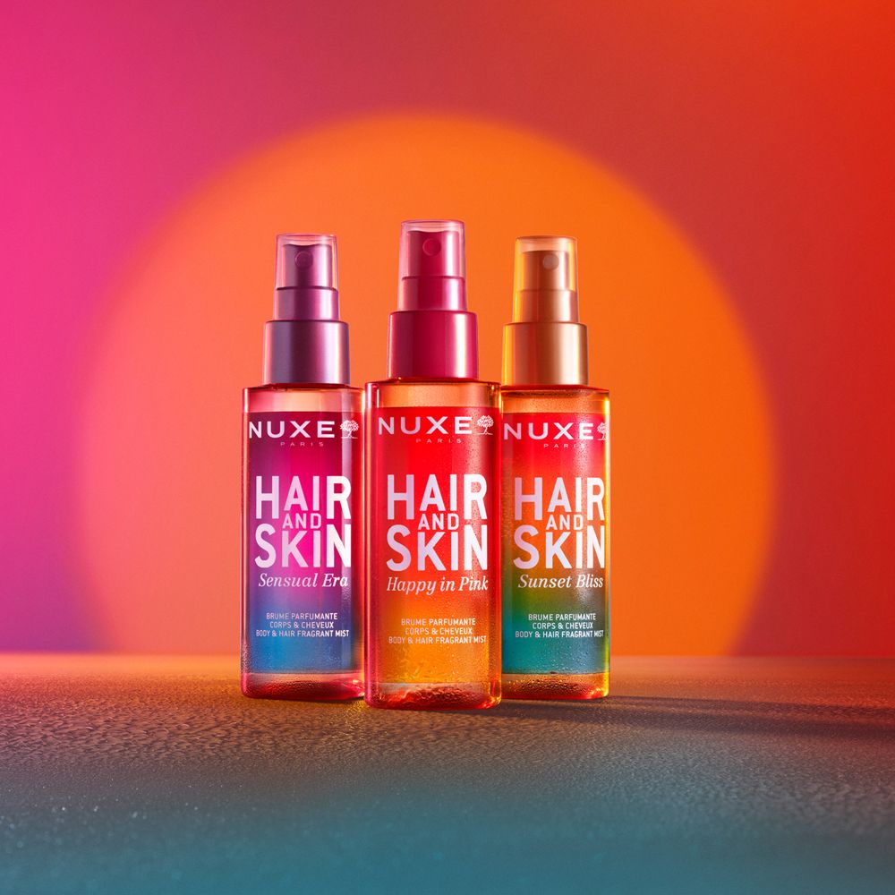 Drei NUXE® Hair and Skin Sprays. Farben: Sensual Era, Happy in Pink, Sunset Bliss. Text: Hair and Skin, Body & Hair Fragrant Mist.