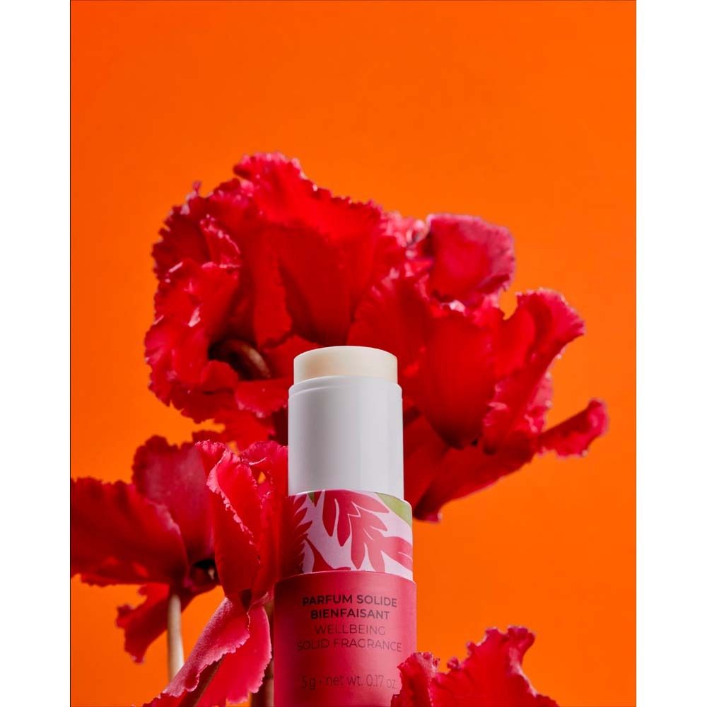 Parfumstick vor rotem Hintergrund mit roten Blüten. Weißer Deckel, weißer Korpus mit floralem Muster und rotem Boden. Text: ROGER&GALLET.