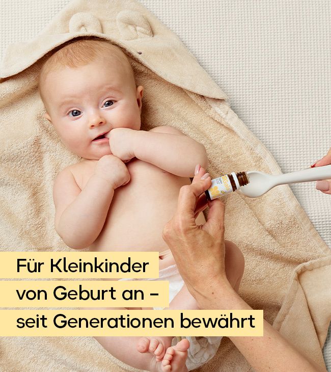 Baby liegt auf einem Handtuch, eine Hand gibt Tropfen aus einer Pipettenflasche auf einen Löffel.