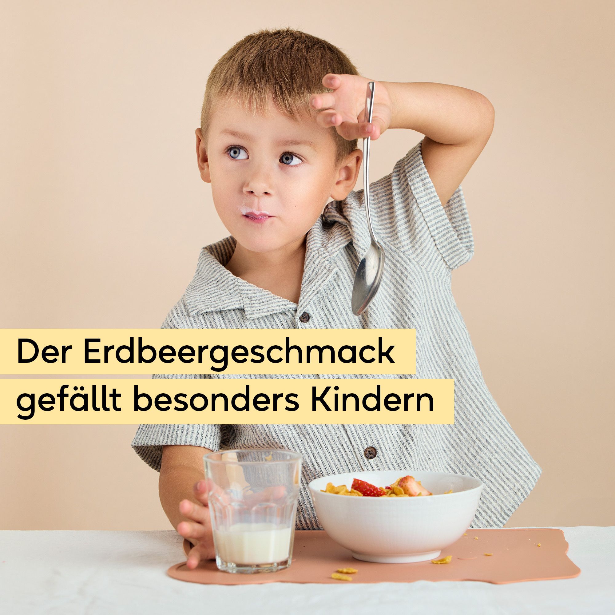 Junge isst Frühstückscerealien mit Erdbeeren und Milch. Text: Der Erdbeergeschmack gefällt besonders Kindern.