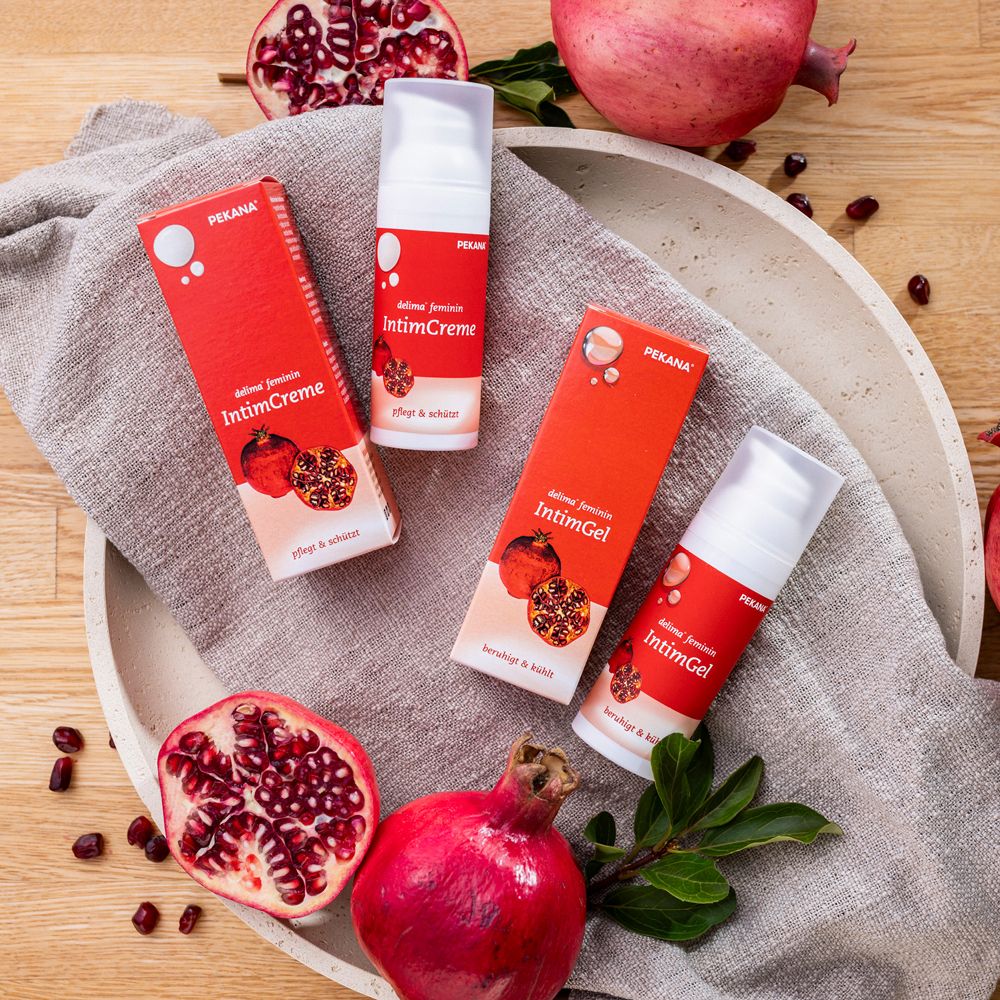 Drei Produkte und Granatäpfel auf Tablett. Produkte: delima feminin IntimGel und Intimcreme. Rote Verpackung.