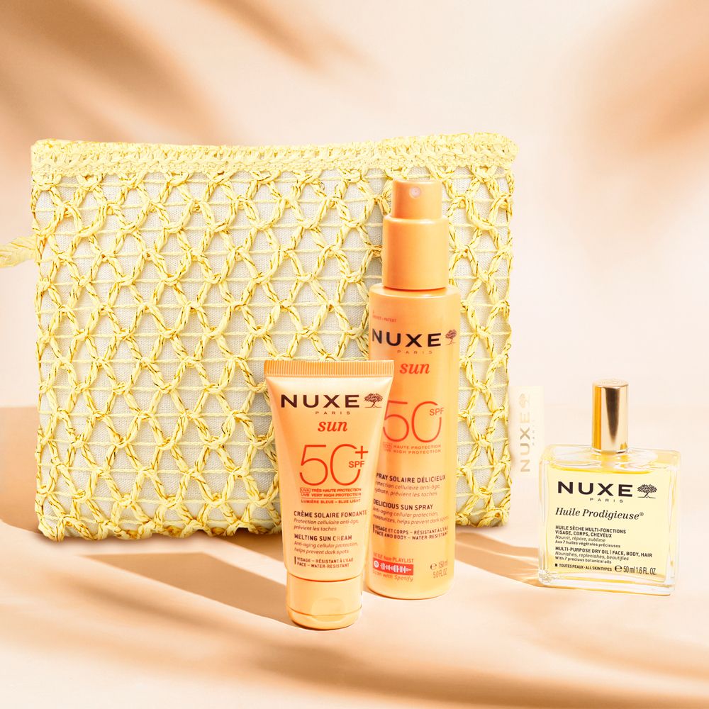 Gelbe Kosmetiktasche mit Sonnenpflegeprodukten. Enthält Sonnencreme, Sonnenspray und Trockenöl. Alle Produkte sind von NUXE.