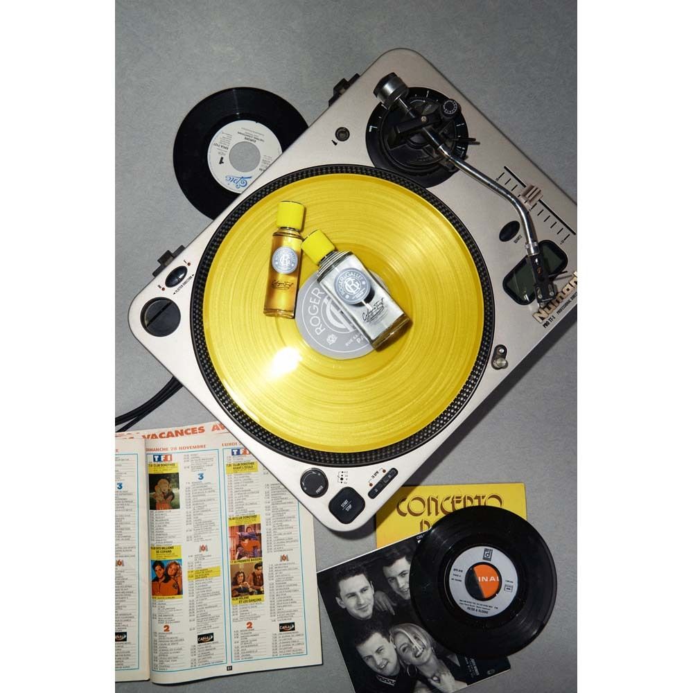 Zwei Flakons auf gelber Schallplatte. Plattenspieler, Schallplatten und Zeitschriften im Hintergrund.