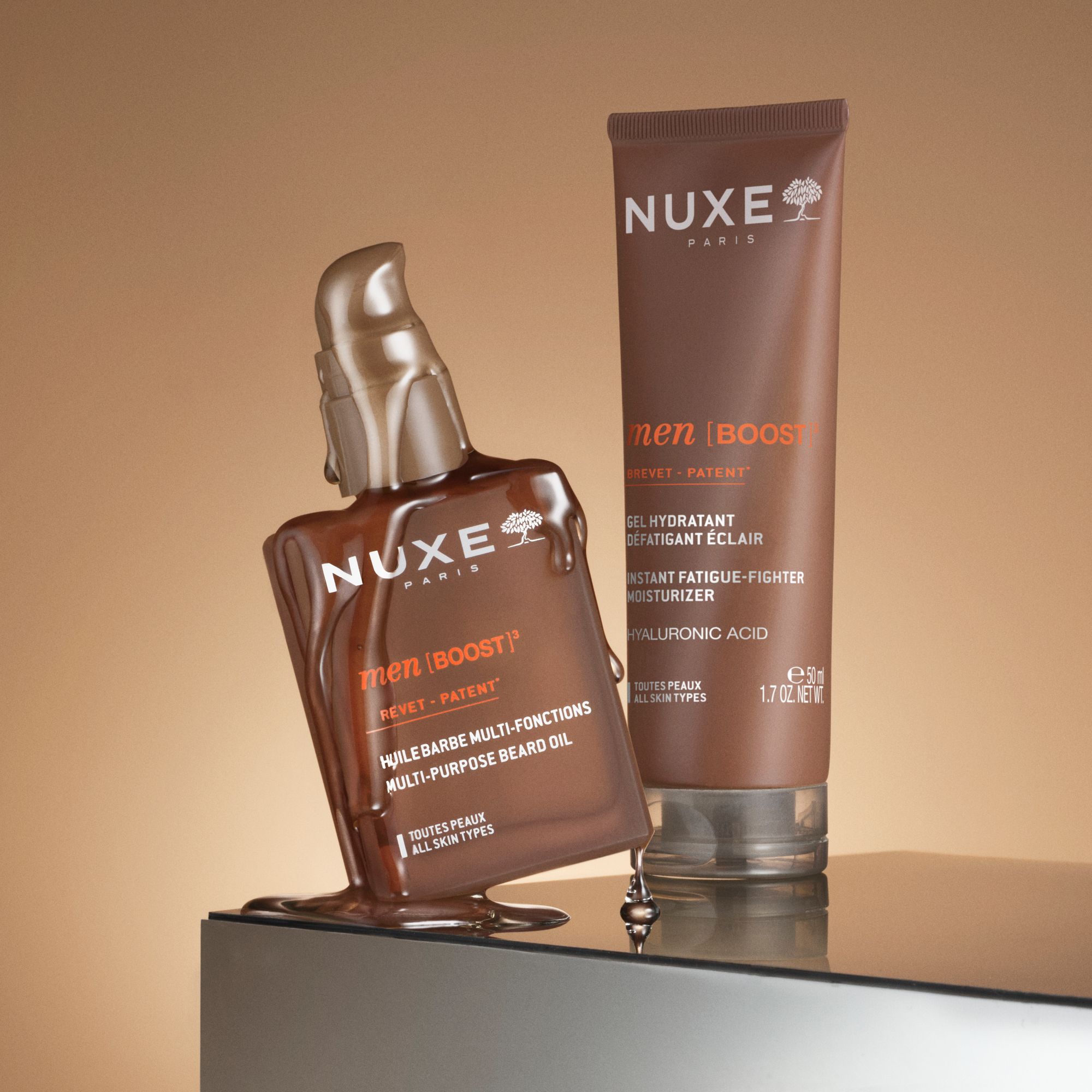 Zwei Produkte: Flasche und Tube. Aufschrift: NUXE PARIS men [BOOST]³. Text: Huile Barbe Multi-Fonctions und Gel Hydratant.