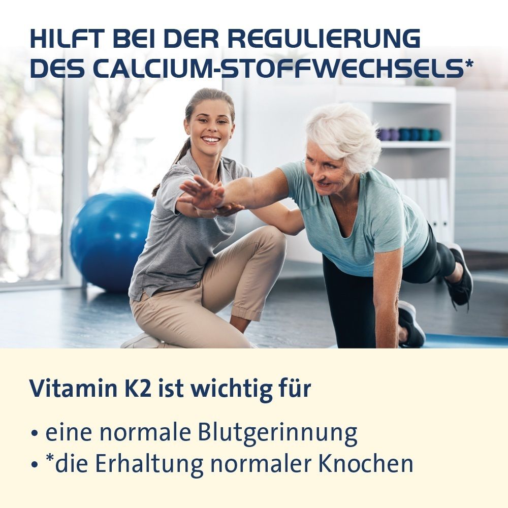 Zwei Frauen in Sportkleidung üben eine Übung aus, eine hilft der anderen. Im Hintergrund ein Gymnastikball.