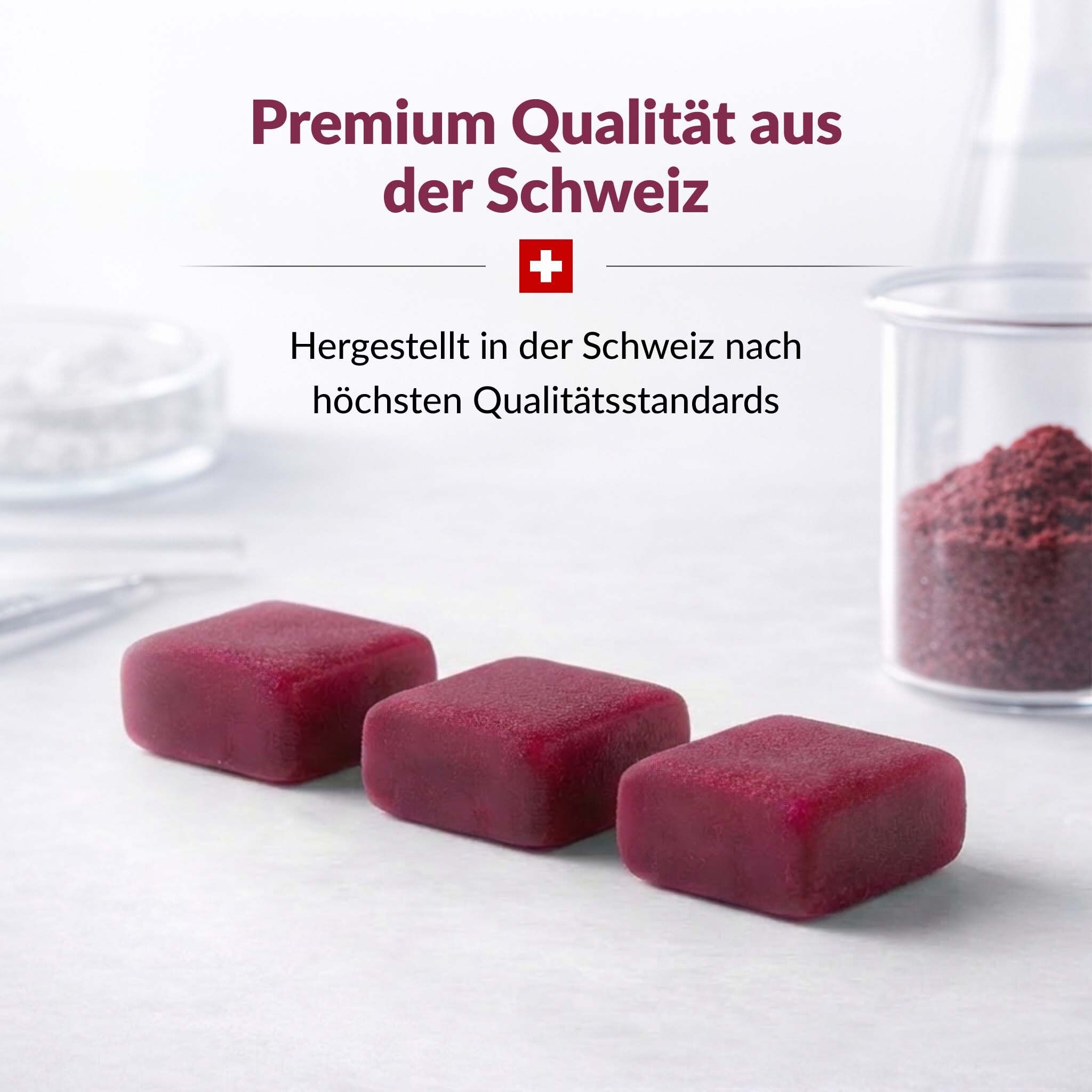 Drei Kautabletten. Text: Premium Qualität aus der Schweiz. Schweizer Kreuz. Hintergrund: Laborutensilien.