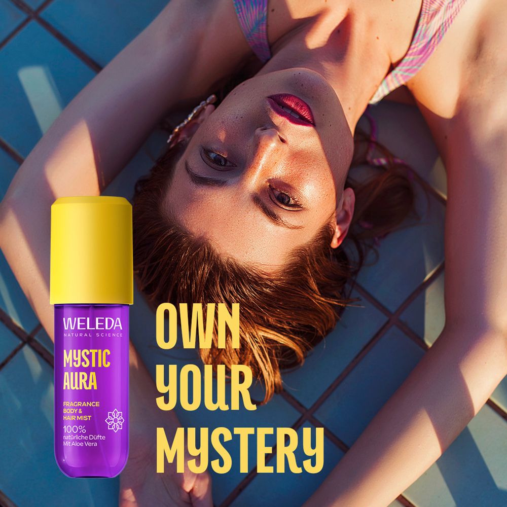 Frau liegt auf blauem Boden. Neben ihr die lila Flasche mit gelbem Deckel. Text: OWN YOUR MYSTERY.