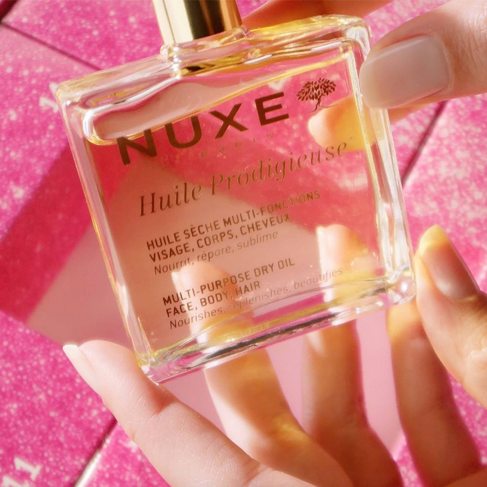 Eine Hand hält eine Flasche Nuxe Huile Prodigieuse Multi-Purpose Dry Oil.