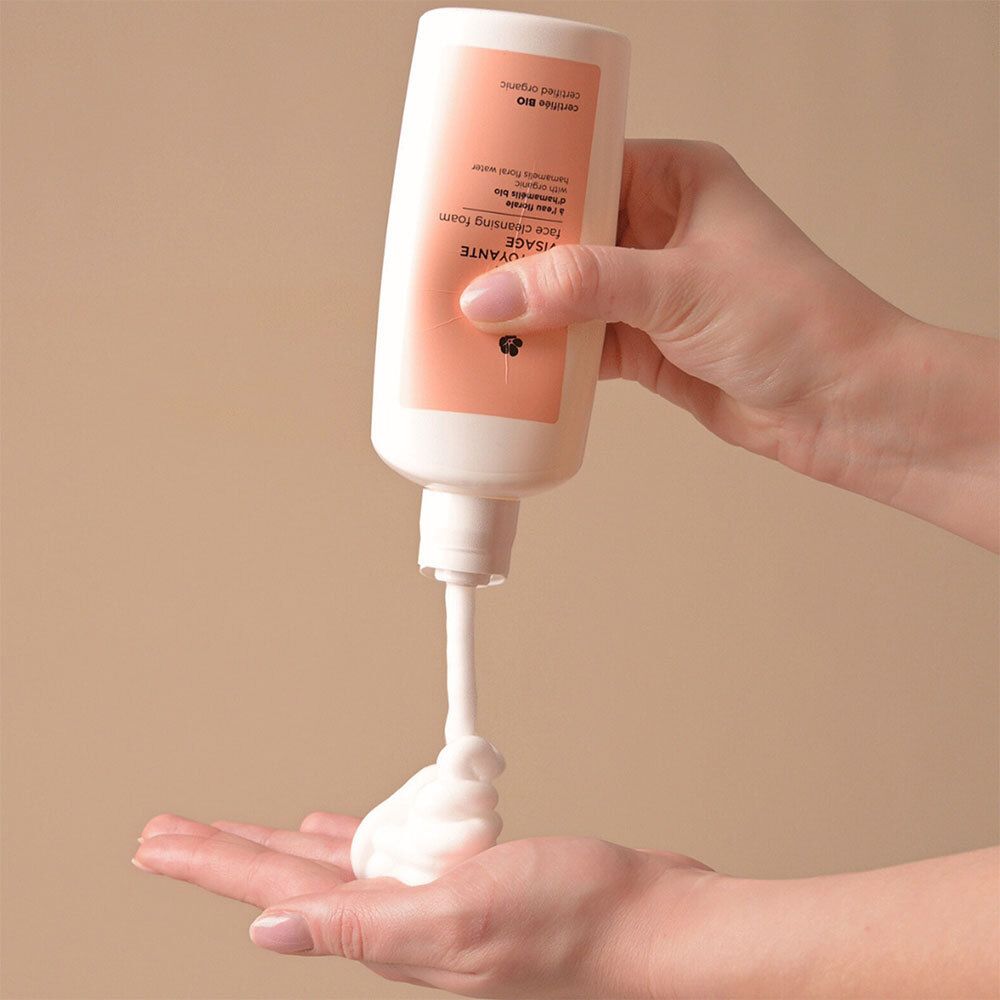 Hand drückt Avril Gesichtsreinigungsschaum aus einer Flasche in die Handfläche.
