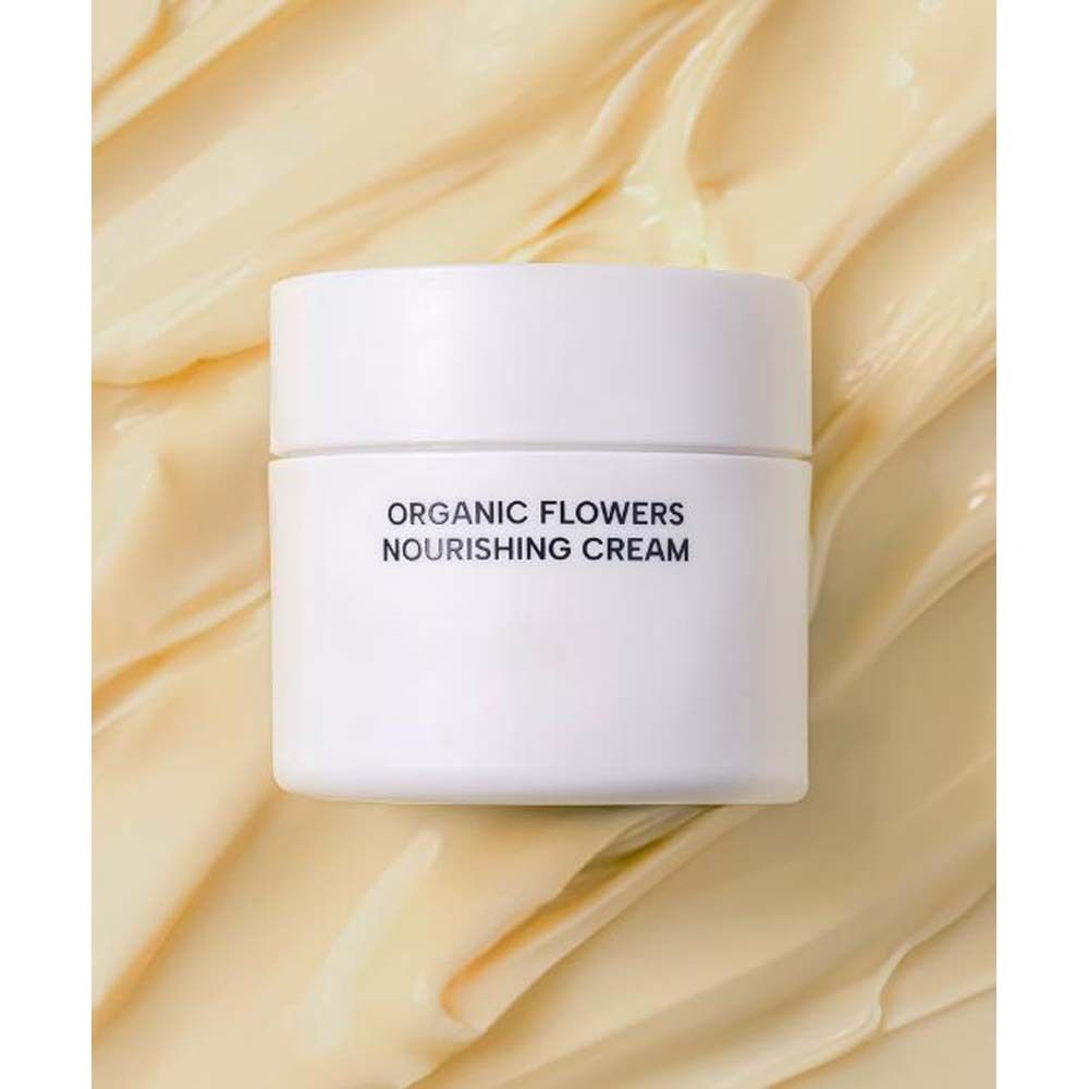 Weißes Tiegel auf cremefarbenem Untergrund. Aufschrift: ORGANIC FLOWERS NOURISHING CREAM.