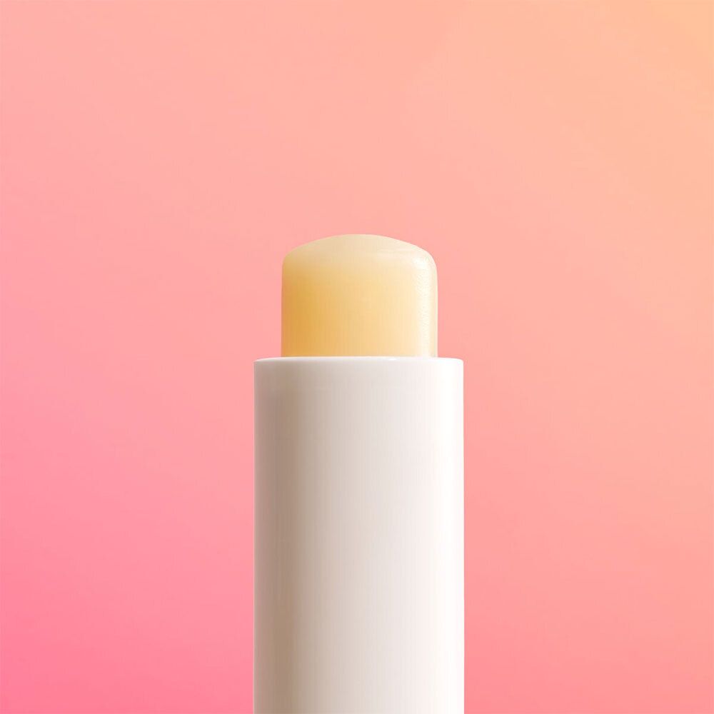 Weißer Lippenbalsam-Stift. Gelbe Spitze. Auf rosa-orangefarbenem Hintergrund.